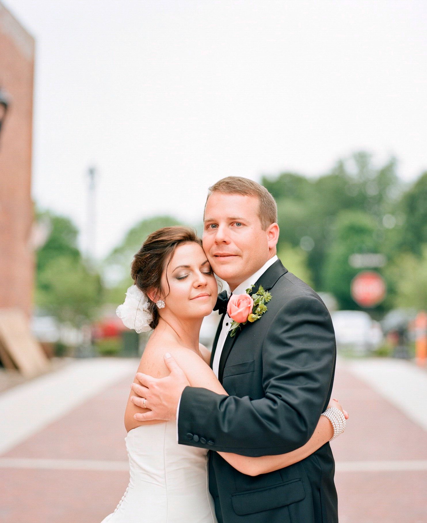 Romantic couple dancing together outdoors in formal wedding attire.