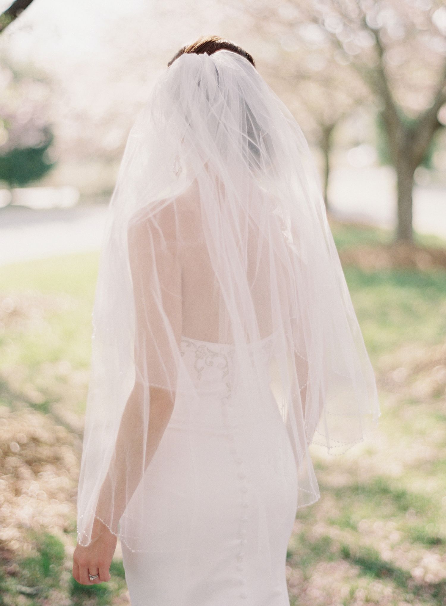 Delicate white bridal veil flowing in the breeze against a soft outdoor background.