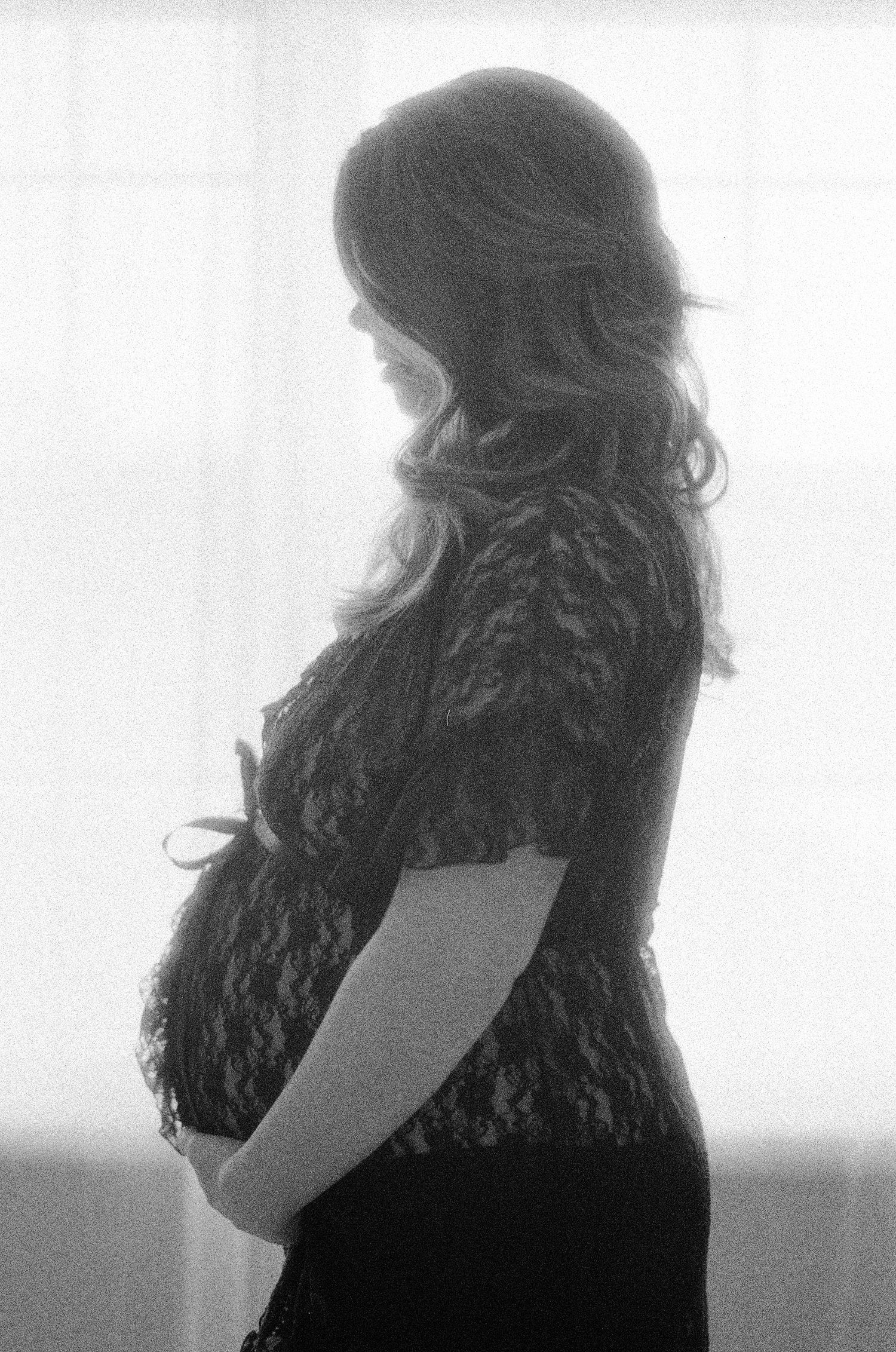 Artistic black and white silhouette portrait against bright window light.