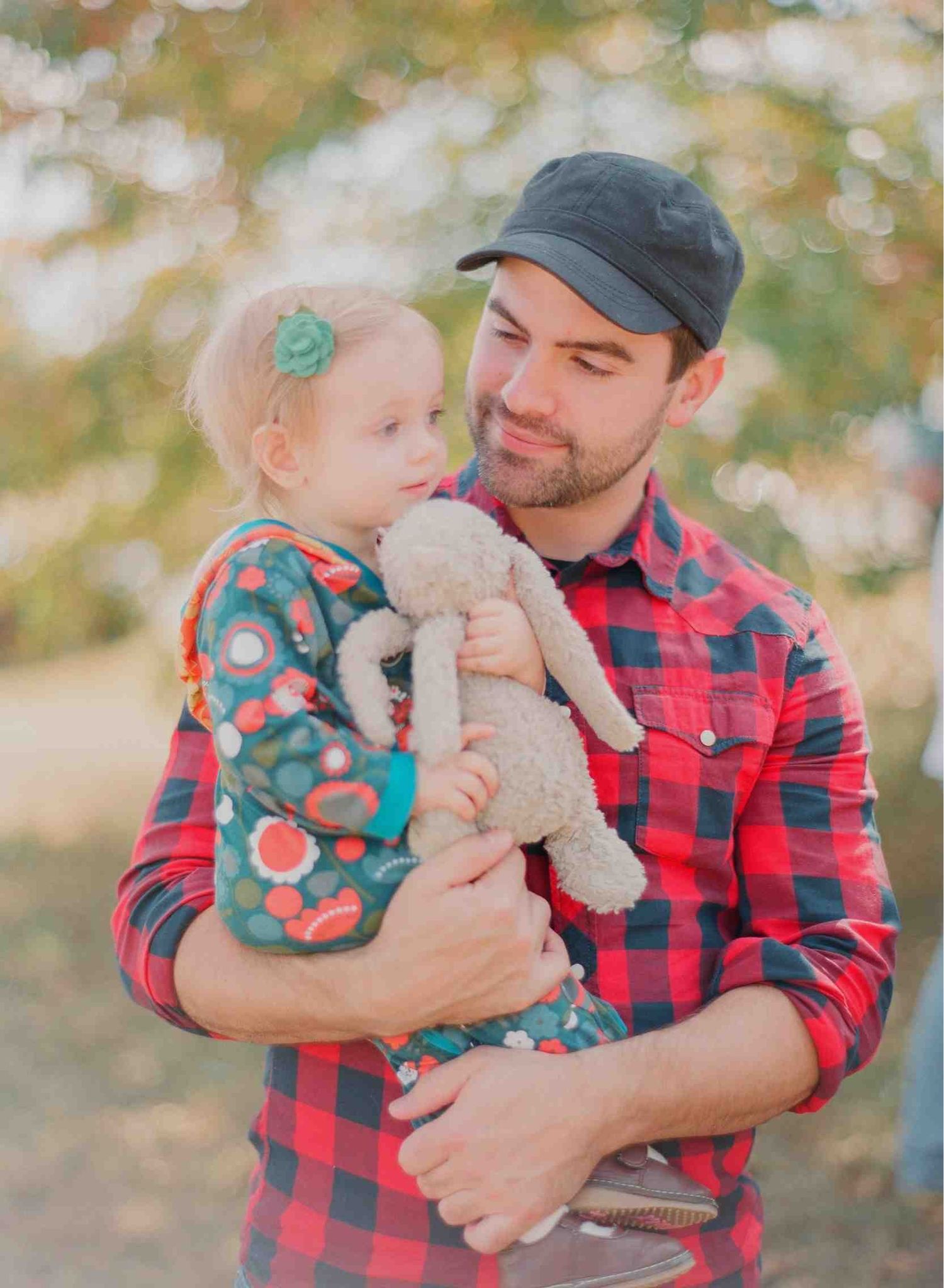 Outdoor family moment with plaid shirt and stuffed animal in autumn setting.