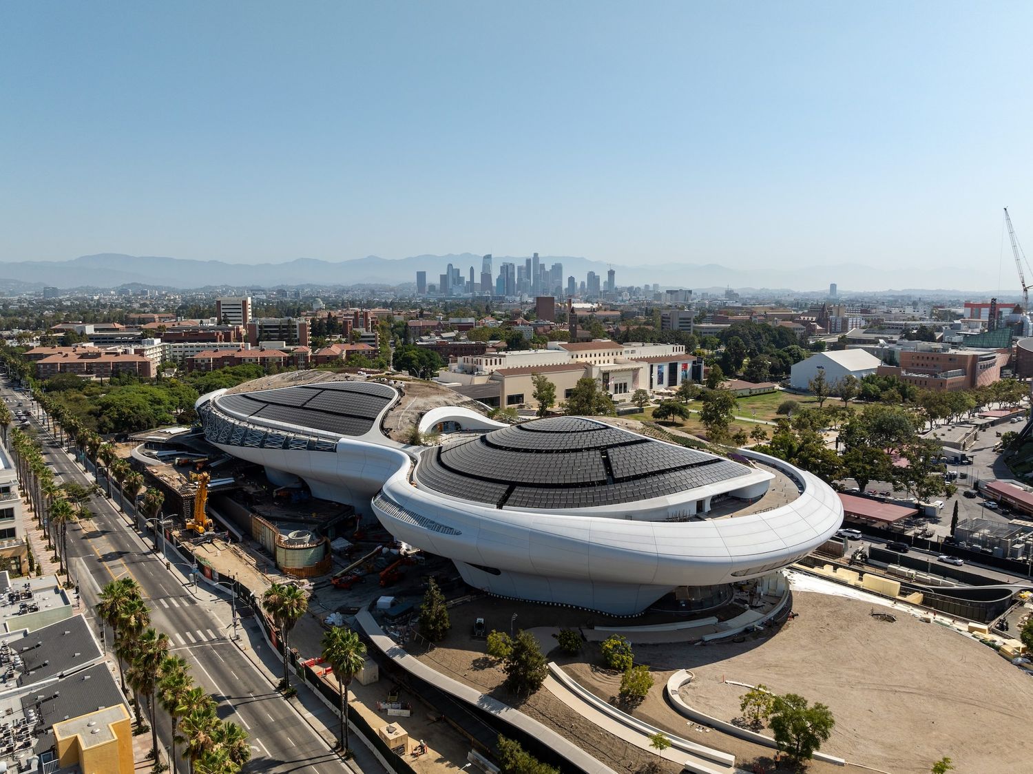 Wide-angle aerial view showing the scale of stadium construction project within its urban context.