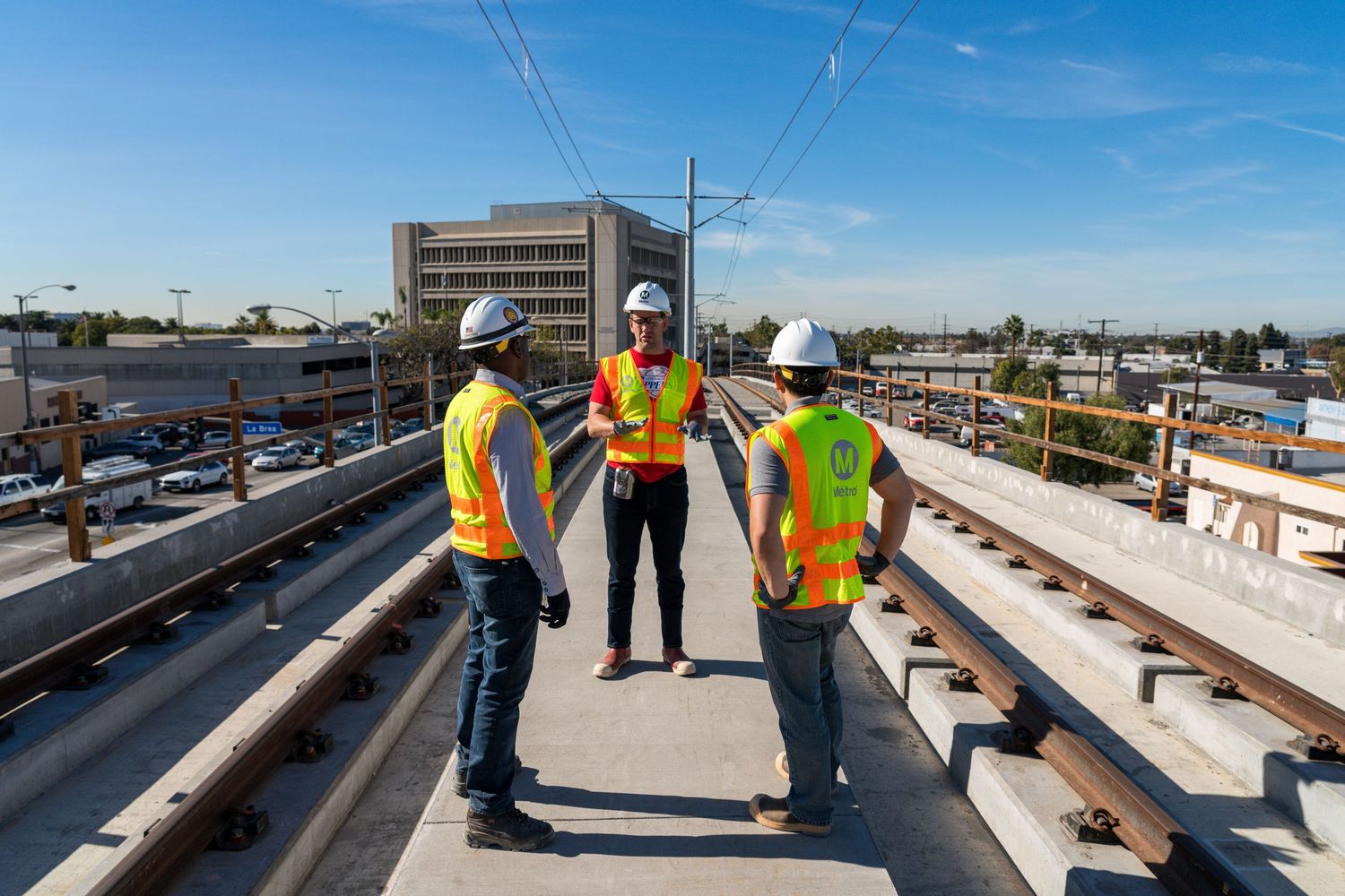 Rail workers in safety gear inspect tracks during transit construction project.