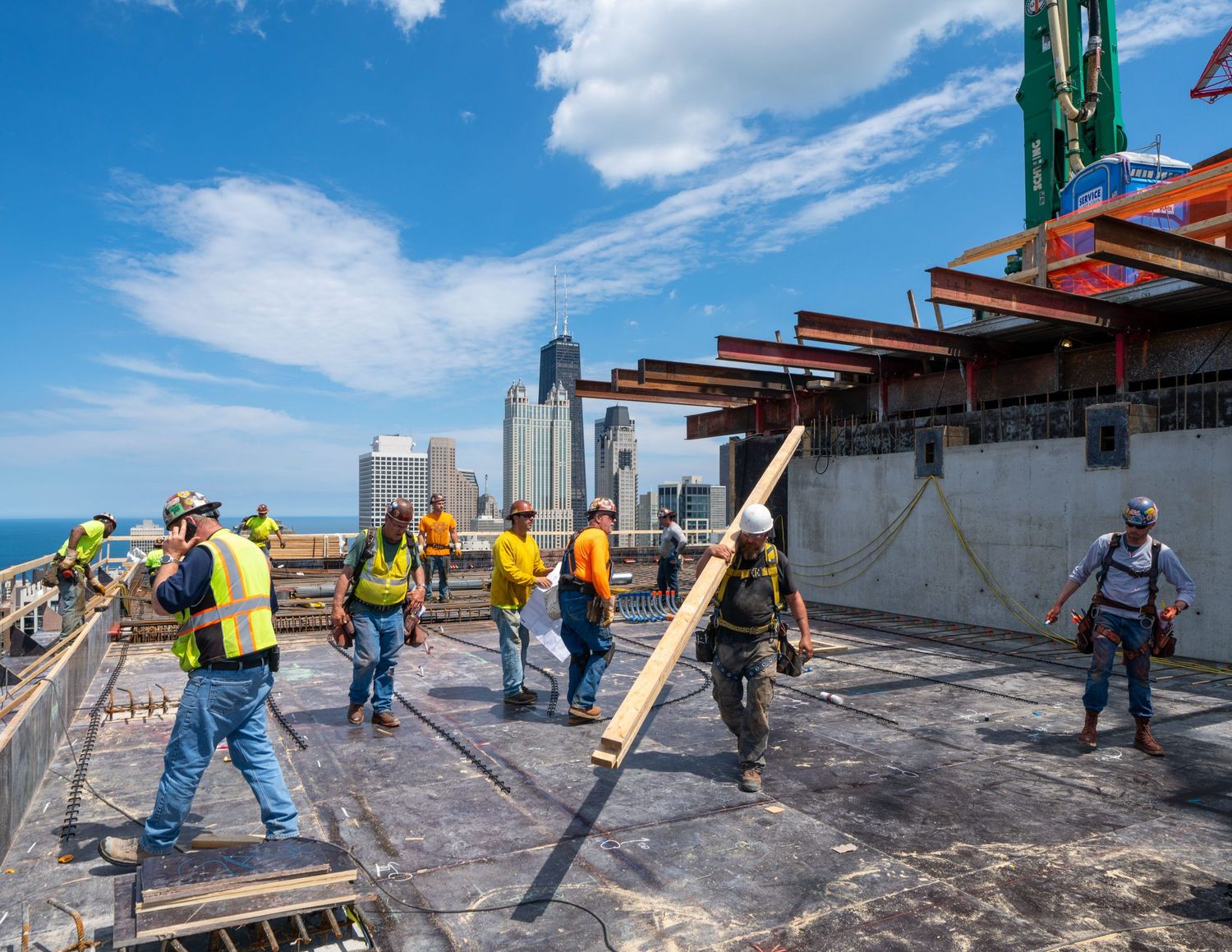 Construction workers on a rooftop working with equipment and materials.