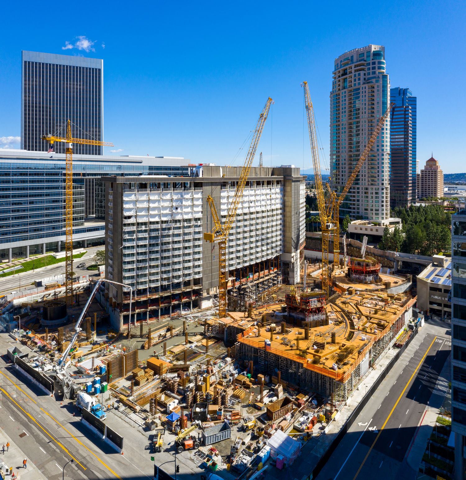 Active construction site with multiple yellow cranes and equipment surrounded by modern buildings.