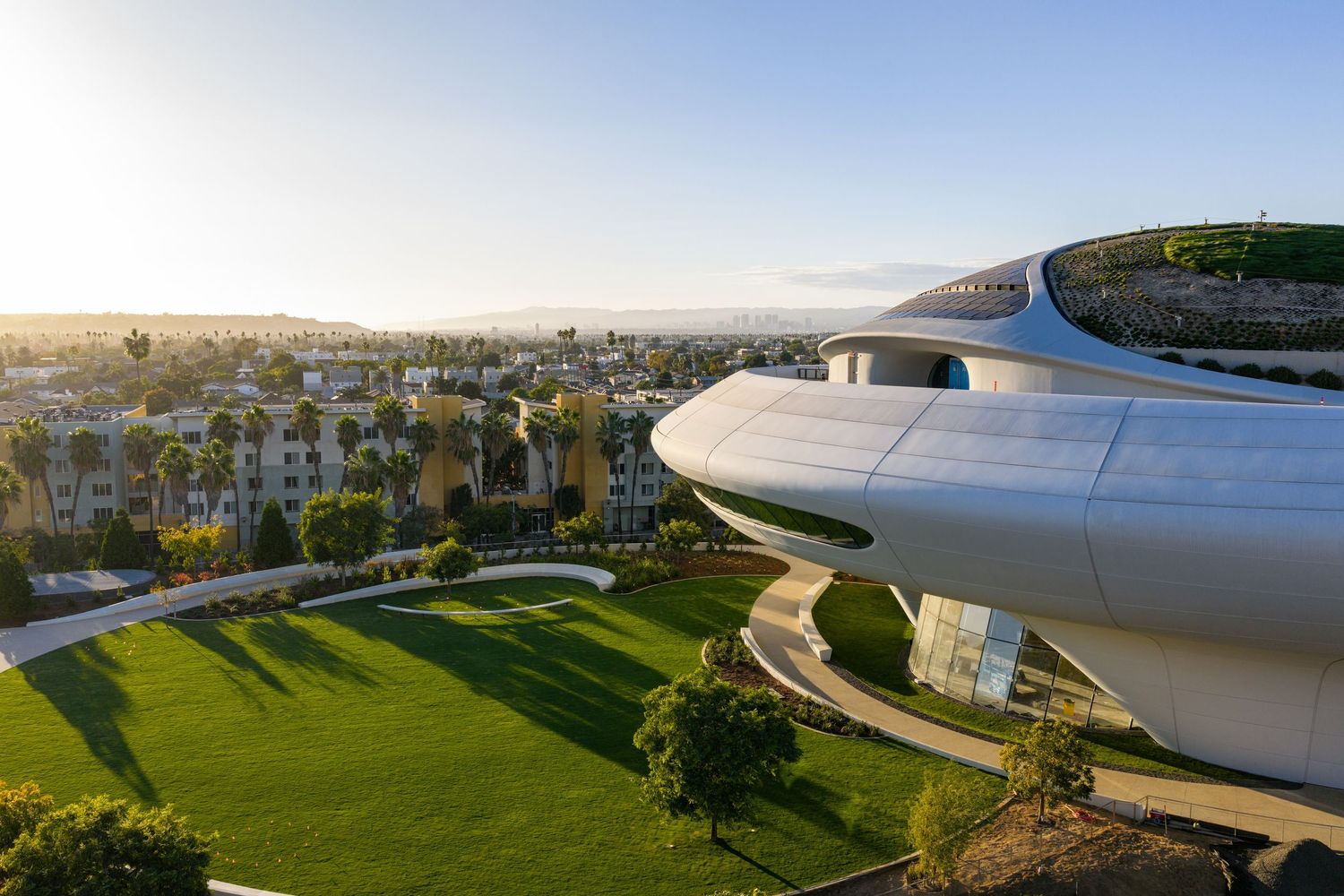 Aerial view of a sleek stadium complex with landscaped grounds and parking areas.