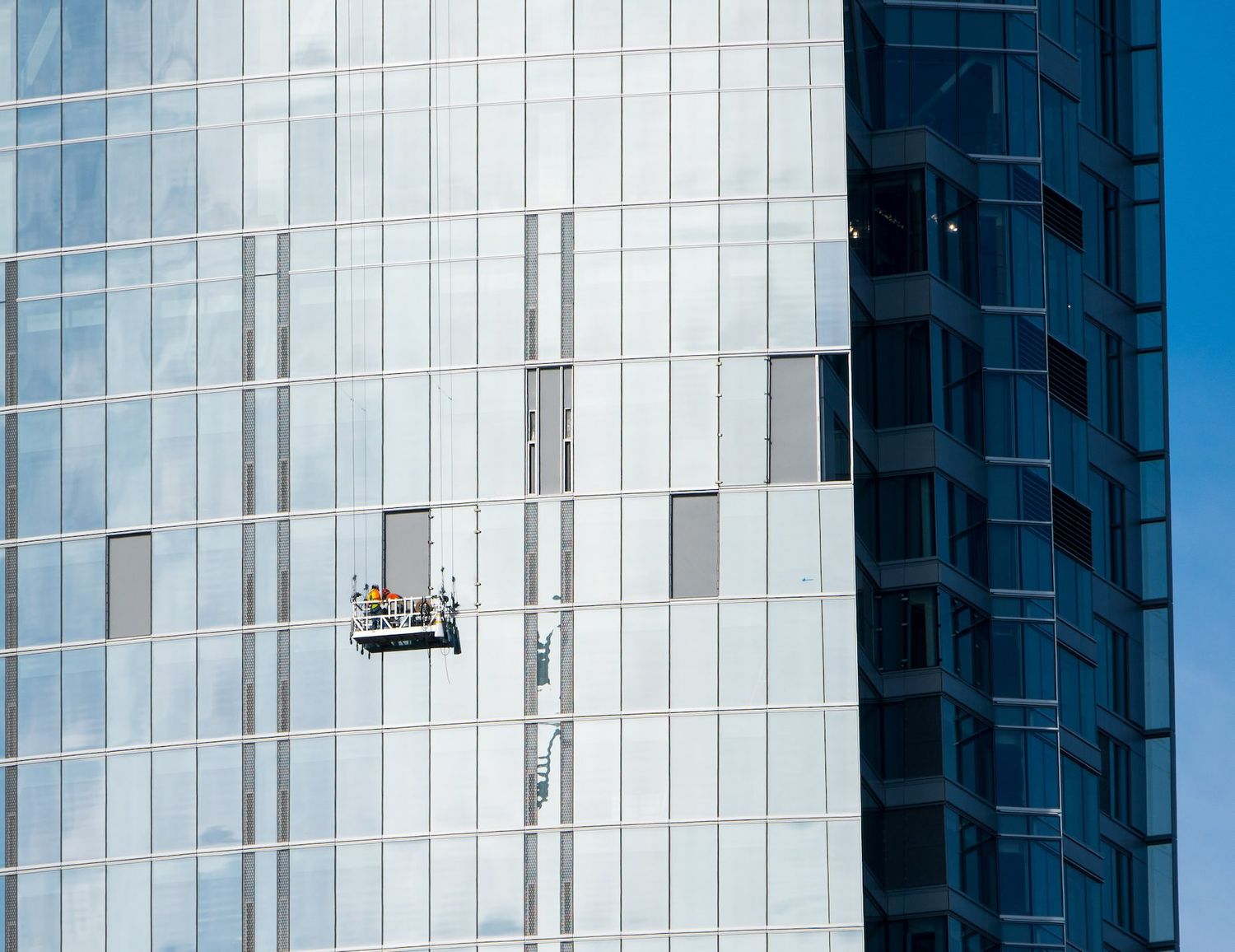 Modern glass building exterior with geometric white panels and reflective windows.