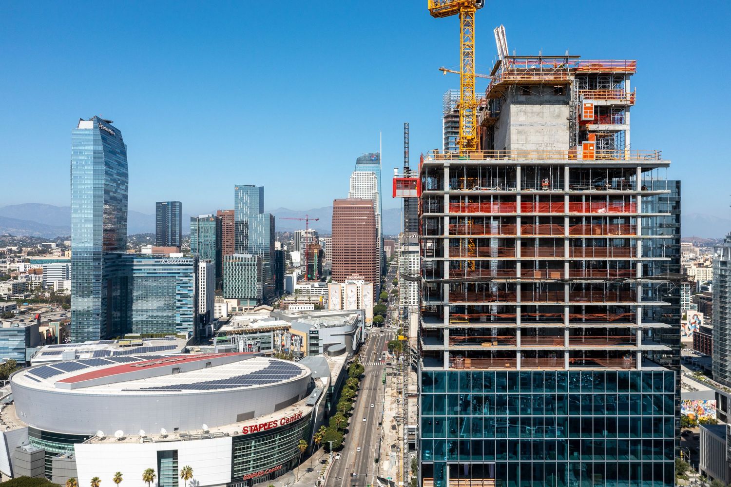 Modern skyscrapers and high-rise construction in downtown Los Angeles with Crypto.com Arena visible.