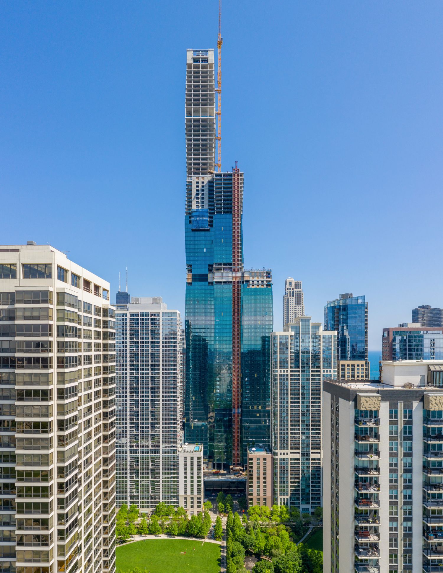 Modern urban skyline with glass high-rise buildings and condominiums against clear blue sky.