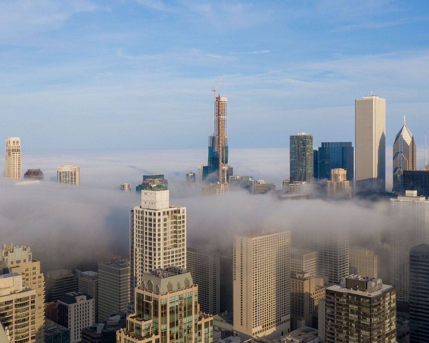 City skyline partially obscured by low-lying fog with tall buildings emerging above the clouds.