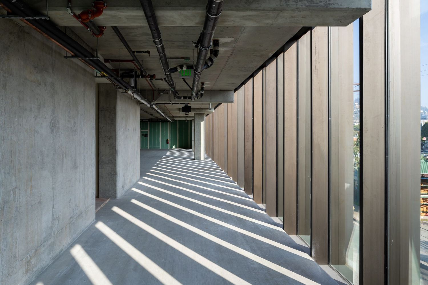 Modern architectural detail showing repeating concrete columns and wood panels creating dramatic shadows and perspective.
