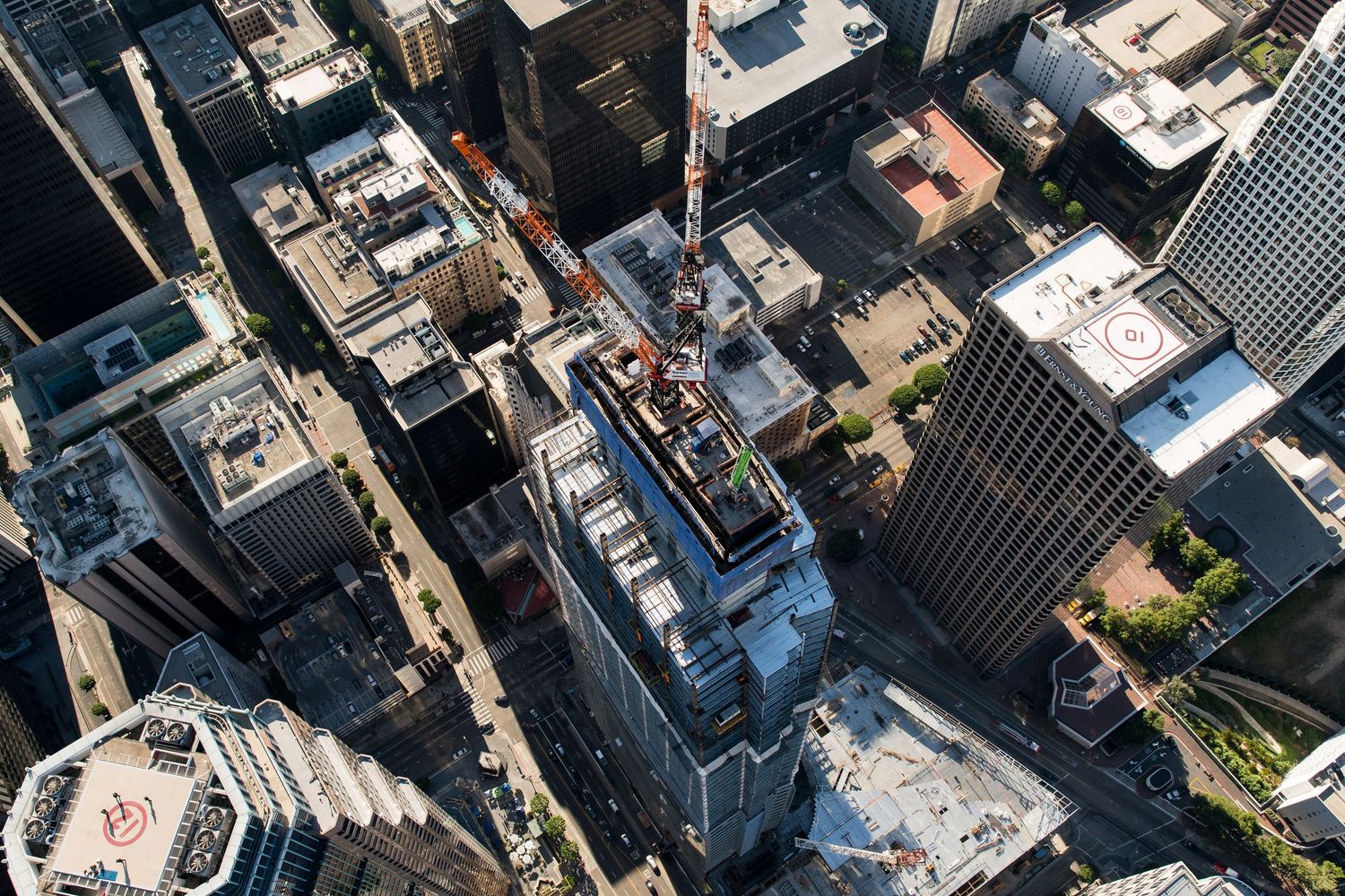 Aerial view of modern skyscrapers and construction cranes in a downtown urban setting.