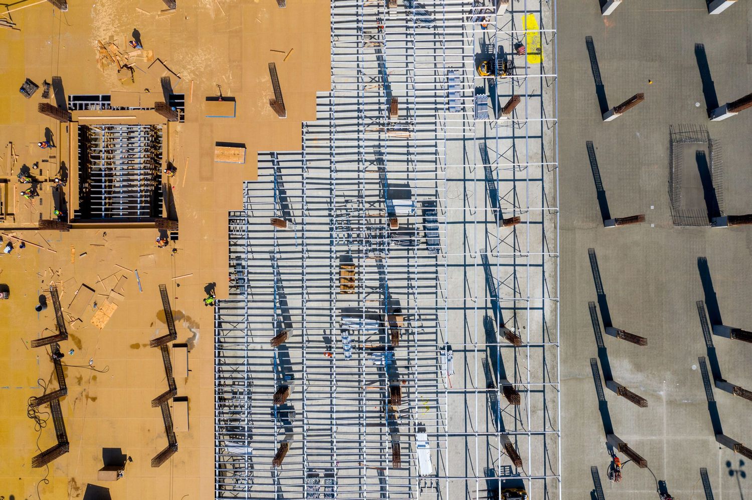 Aerial view of construction workers installing rebar grid pattern on concrete structure.