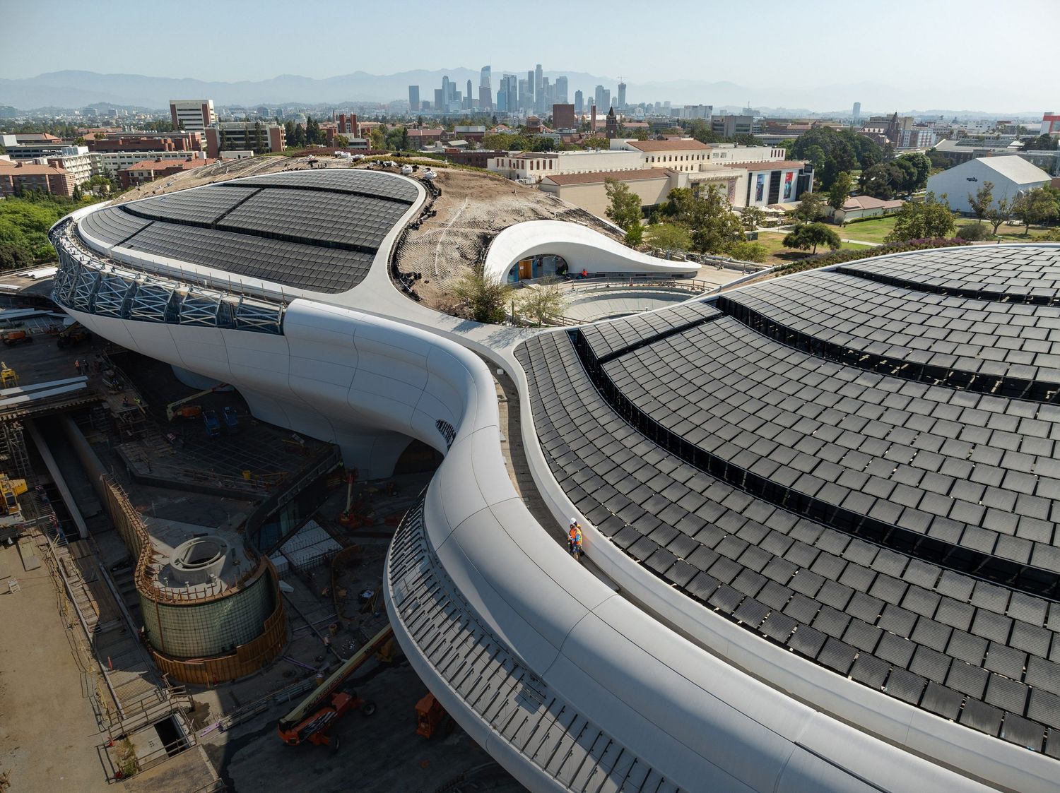 Modern building with curved roof featuring solar panel installation and architectural details.