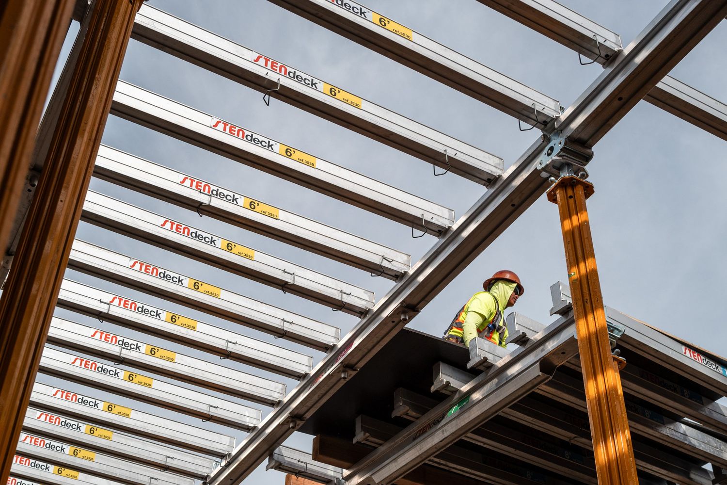 Steel and glass ceiling framework under construction with natural light streaming through.