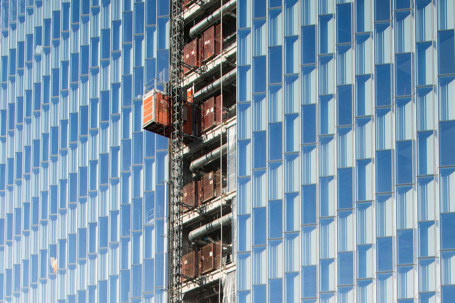 Modern glass office building facade with repeating blue geometric patterns and reflective windows.