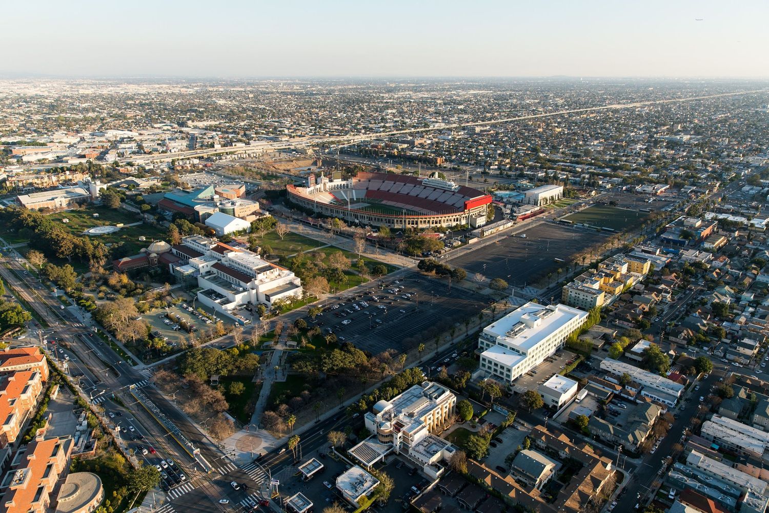 Bird's eye view of a stadium construction site with surrounding cityscape and mountains in the distance.