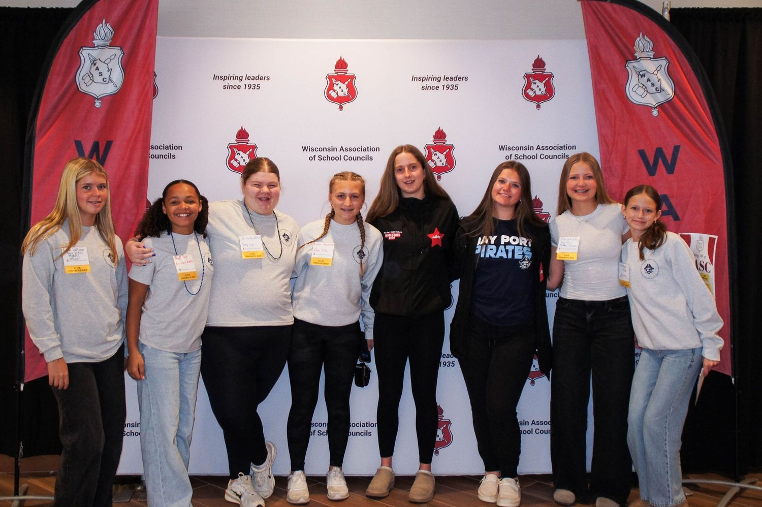 Group of nine students posing in front of Wisconsin Association of School Councils banner.