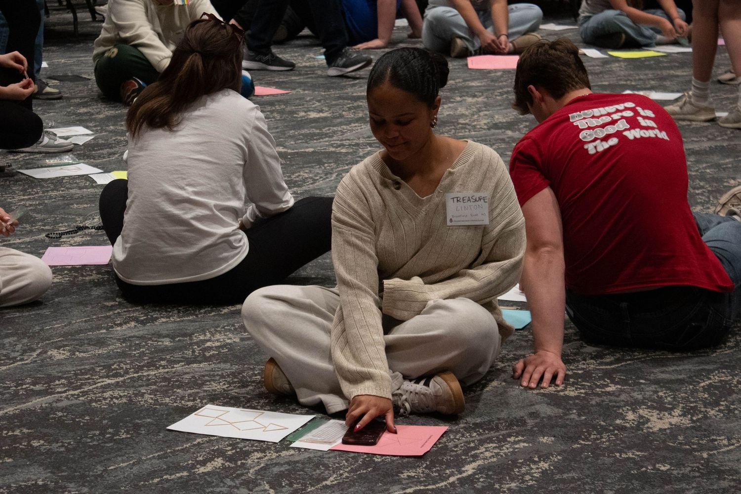 Students sit on the floor engaged in a group activity at a leadership workshop.