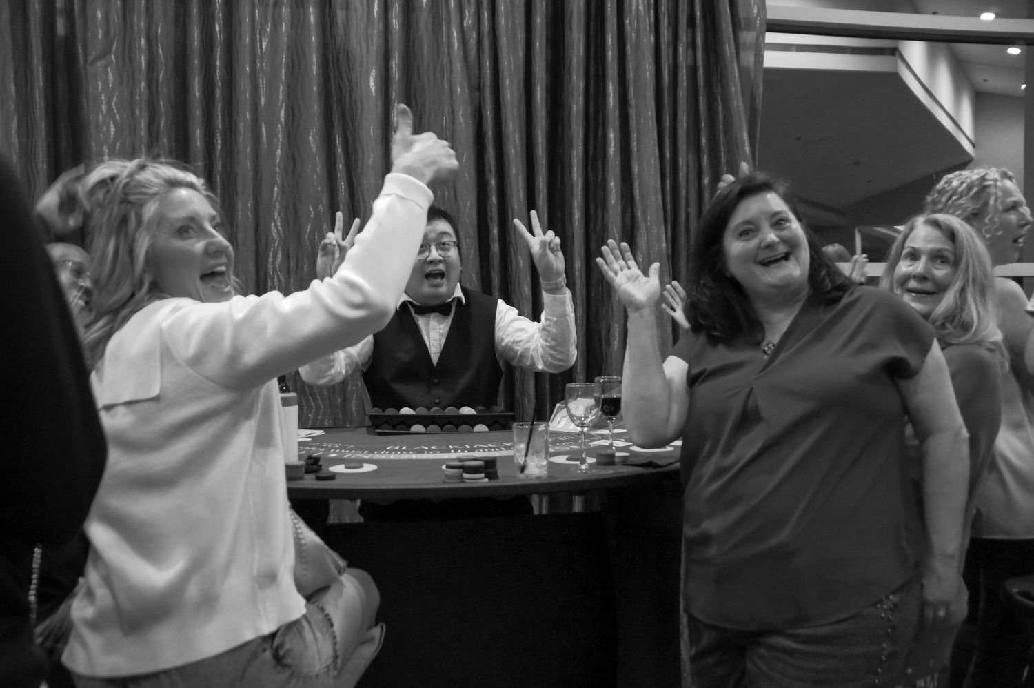 Excited women celebrating a win at a casino roulette table event.