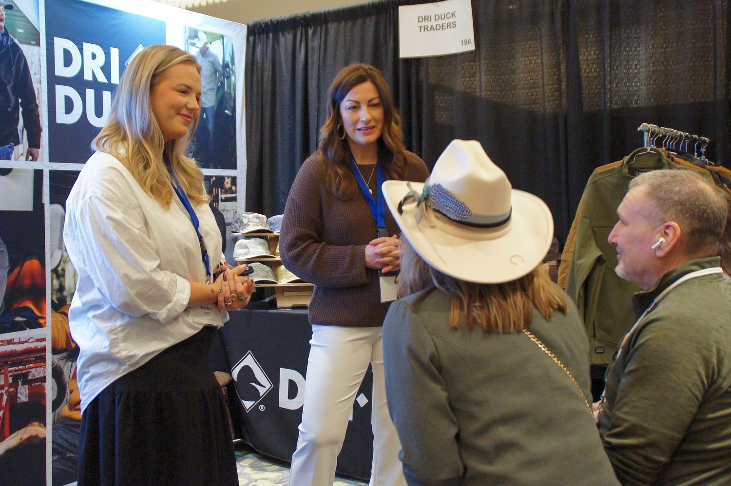 Attendees browsing Dri Duck outdoor apparel at a trade show vendor booth.