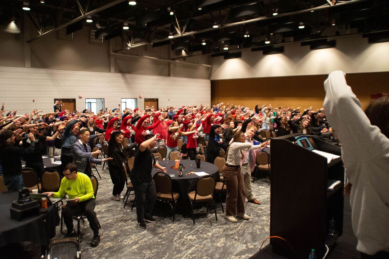 Large crowd of students raising hands during a school leadership conference session.