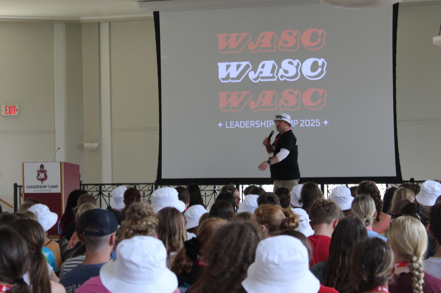 Presenter addresses large audience at WASC Leadership 2025 conference with projection screen.
