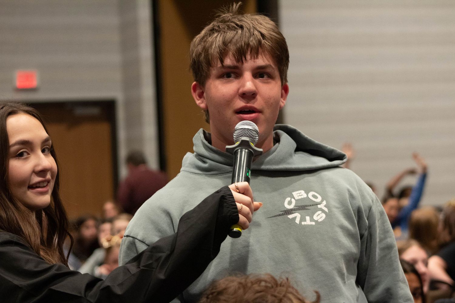 Student speaking into microphone at a school leadership conference event.