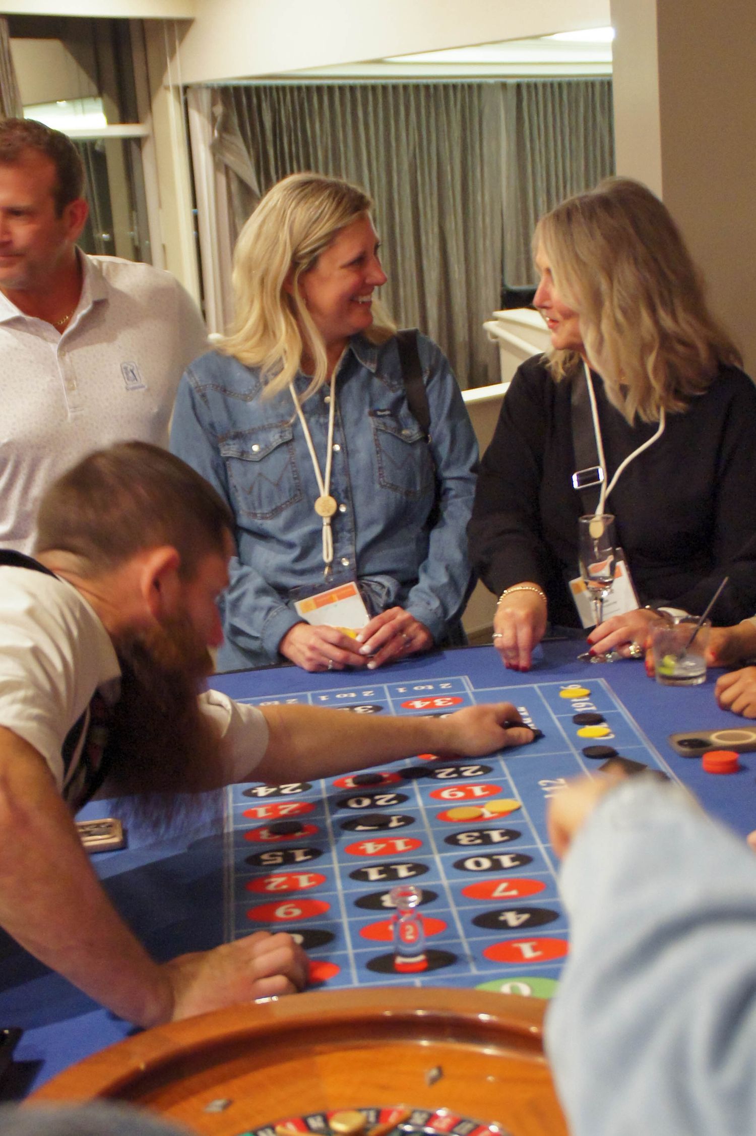 Smiling guests enjoying a roulette table at a casino-themed party event.