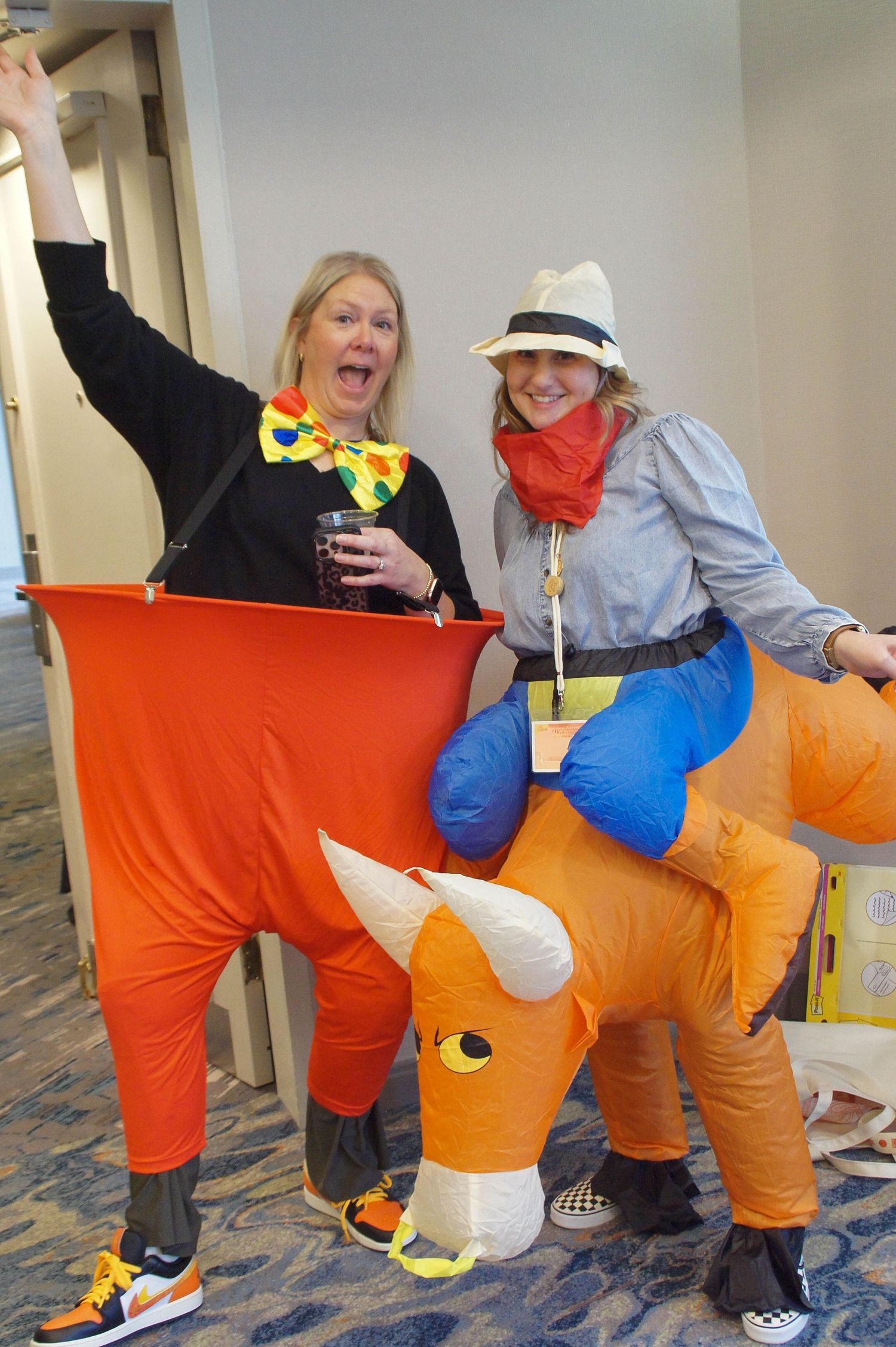 Two women in fun costumes pose with an inflatable bull at NSM 26 Dallas event.