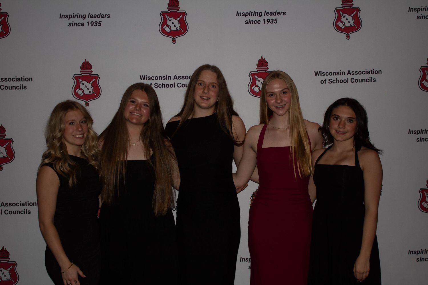 Five students pose together in formal attire at the WASC Leadership Conference backdrop.