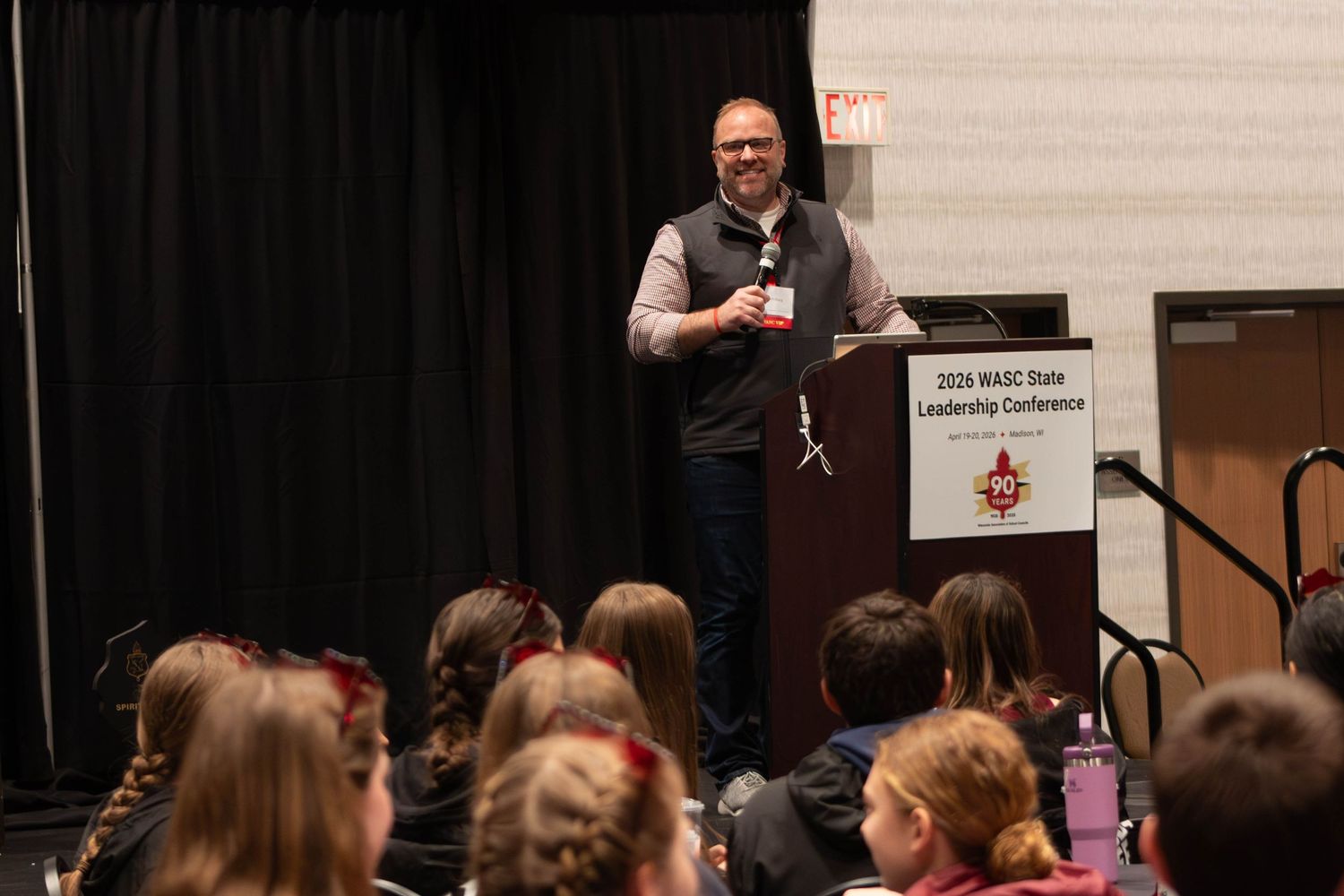 A man speaks at a podium to a seated audience at the 2026 WASC State Leadership Conference.