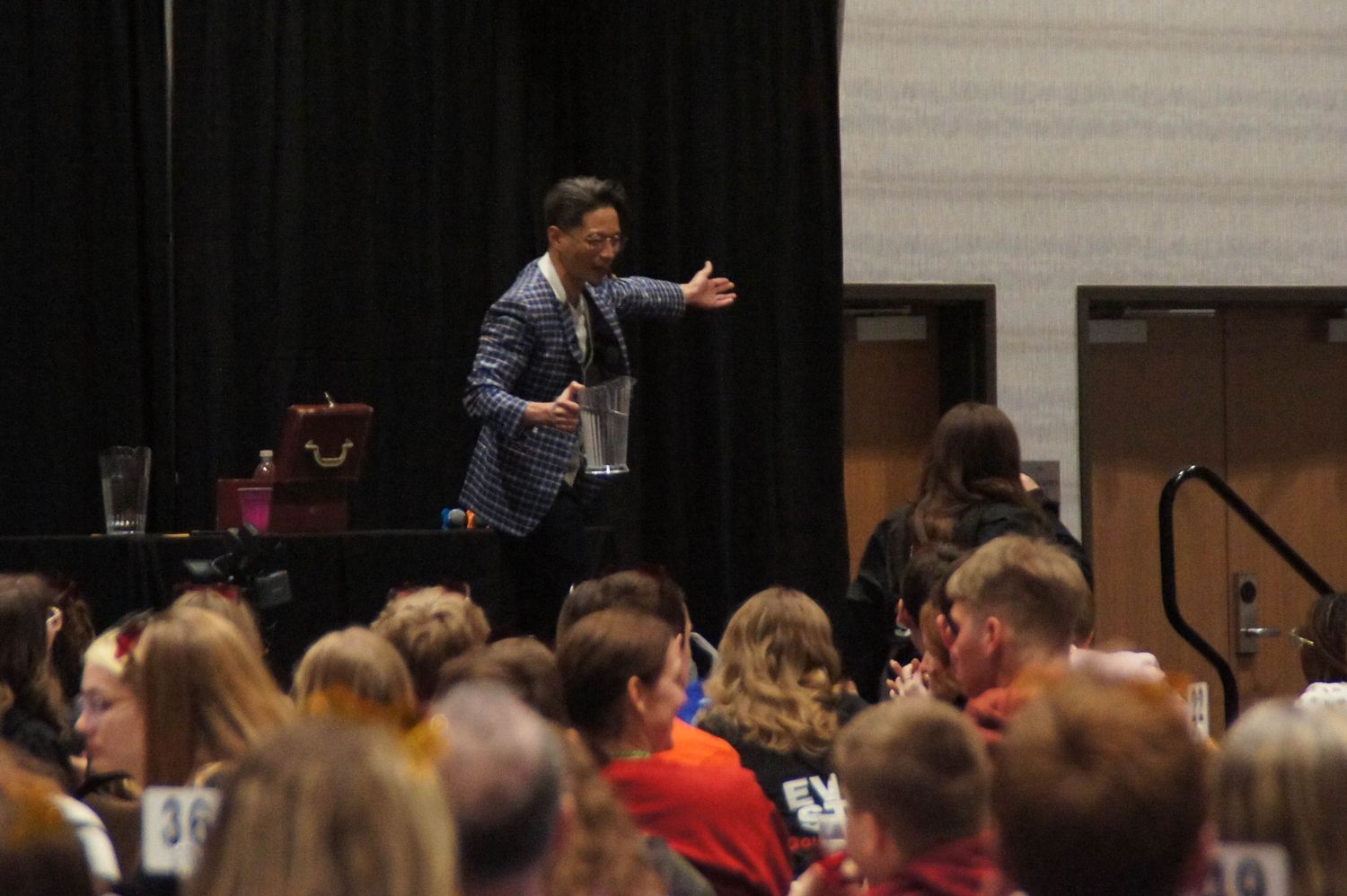 A dynamic speaker gestures to a large audience at a student leadership conference.