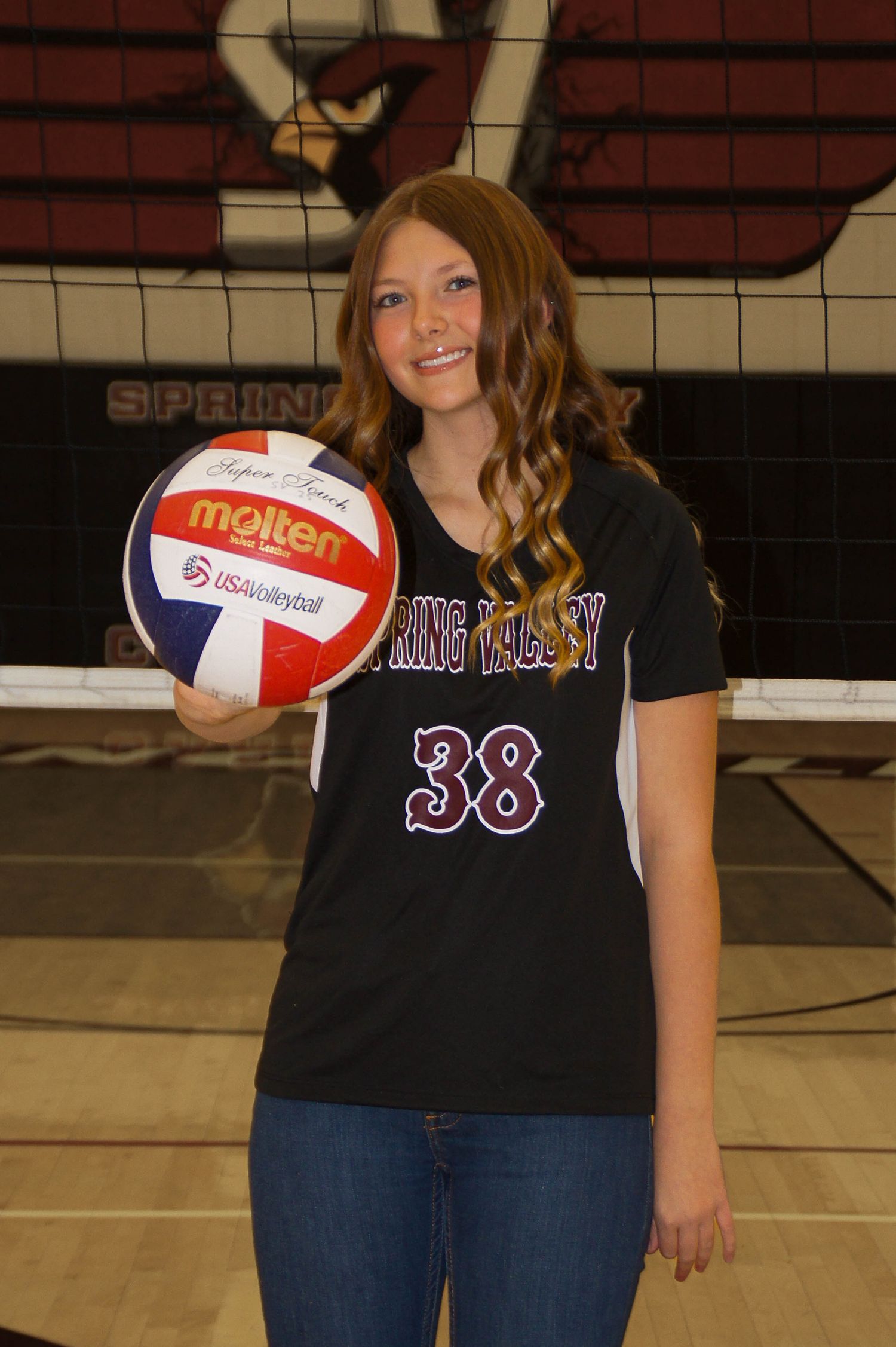 Girl in Spring Valley volleyball jersey number 38 holding Molten volleyball on court.