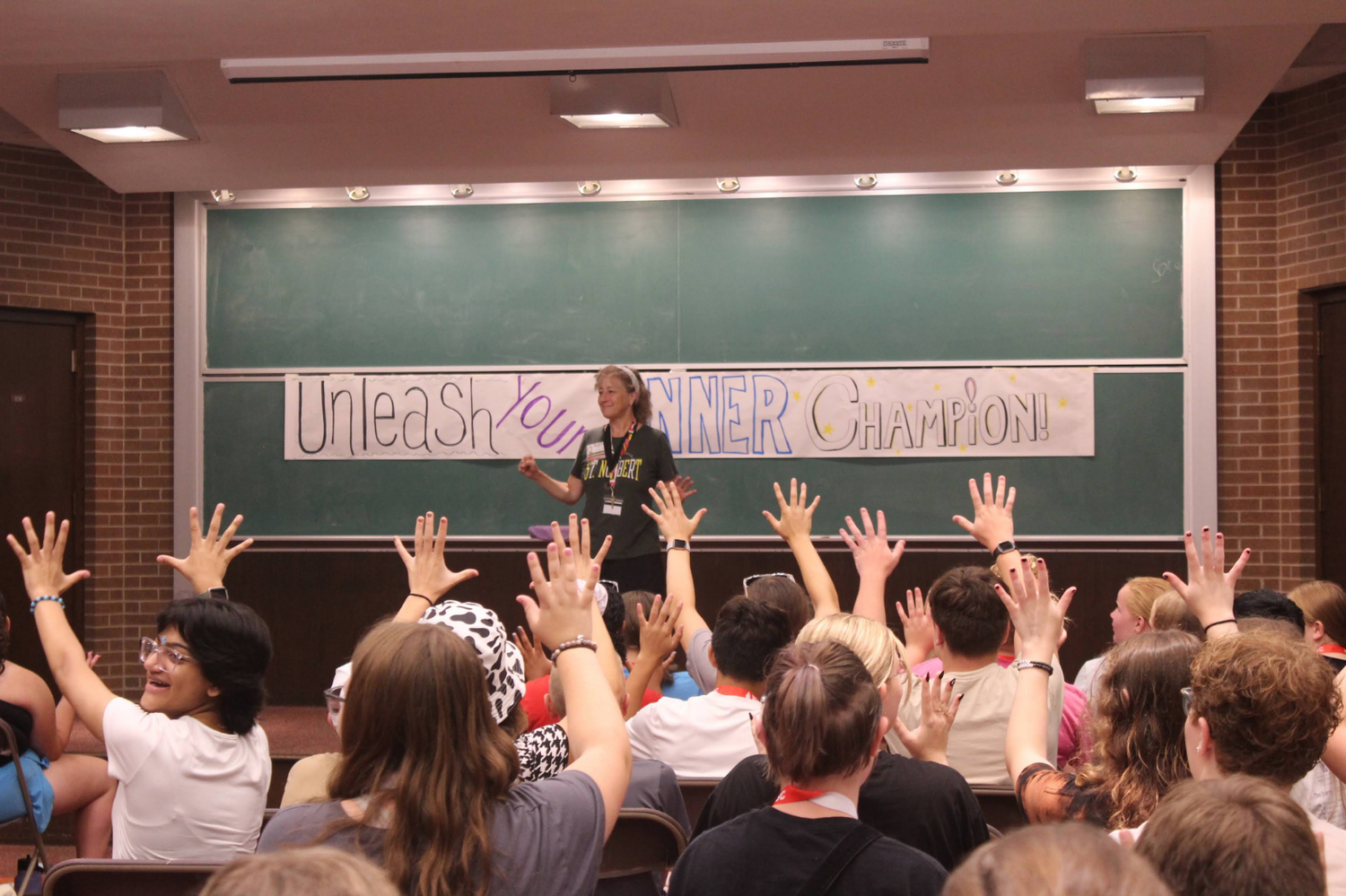 Speaker engages audience with raised hands during an Unleash Your Inner Champion workshop.