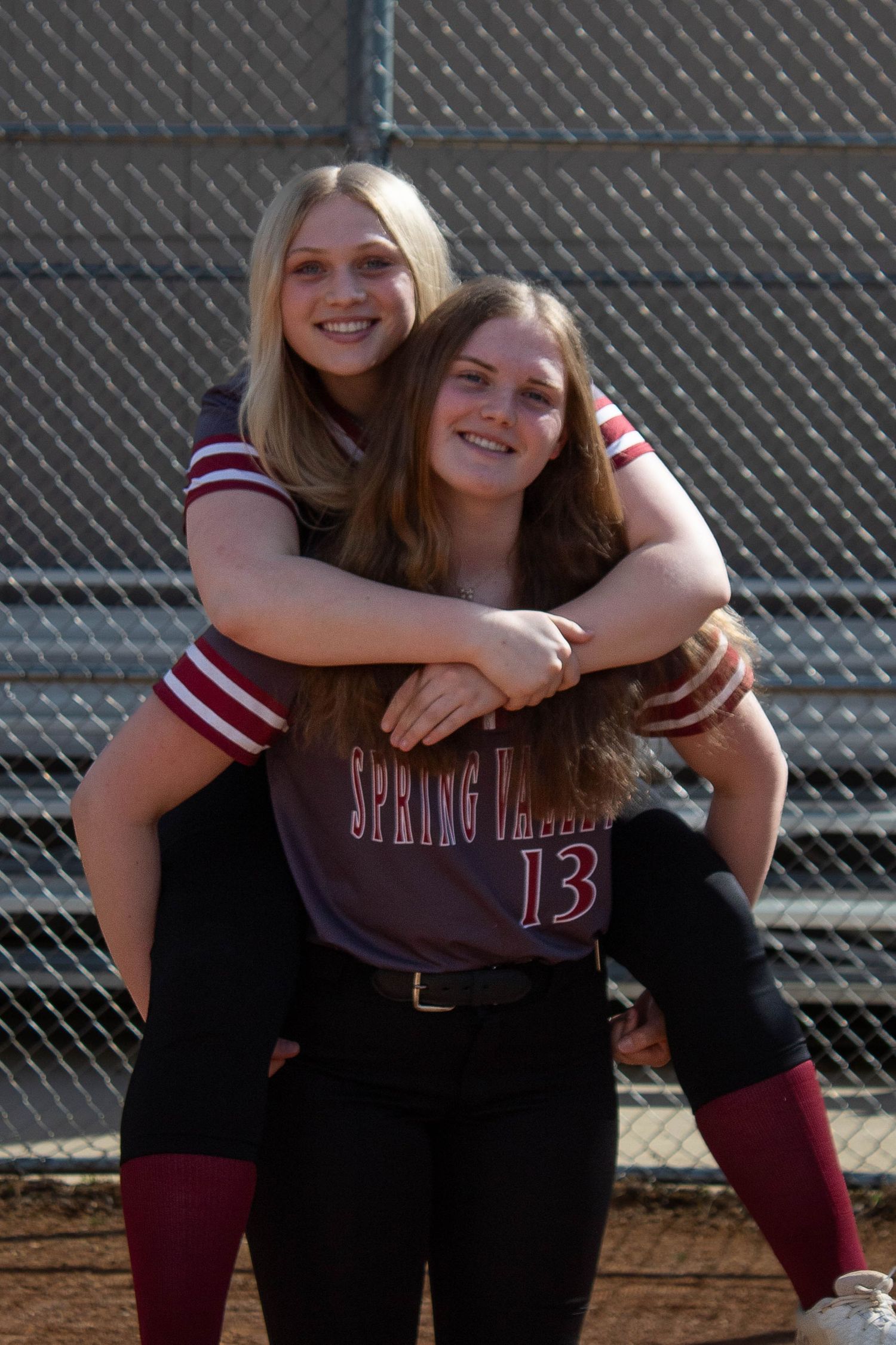 Two Spring Valley softball teammates share a piggyback pose on the field.