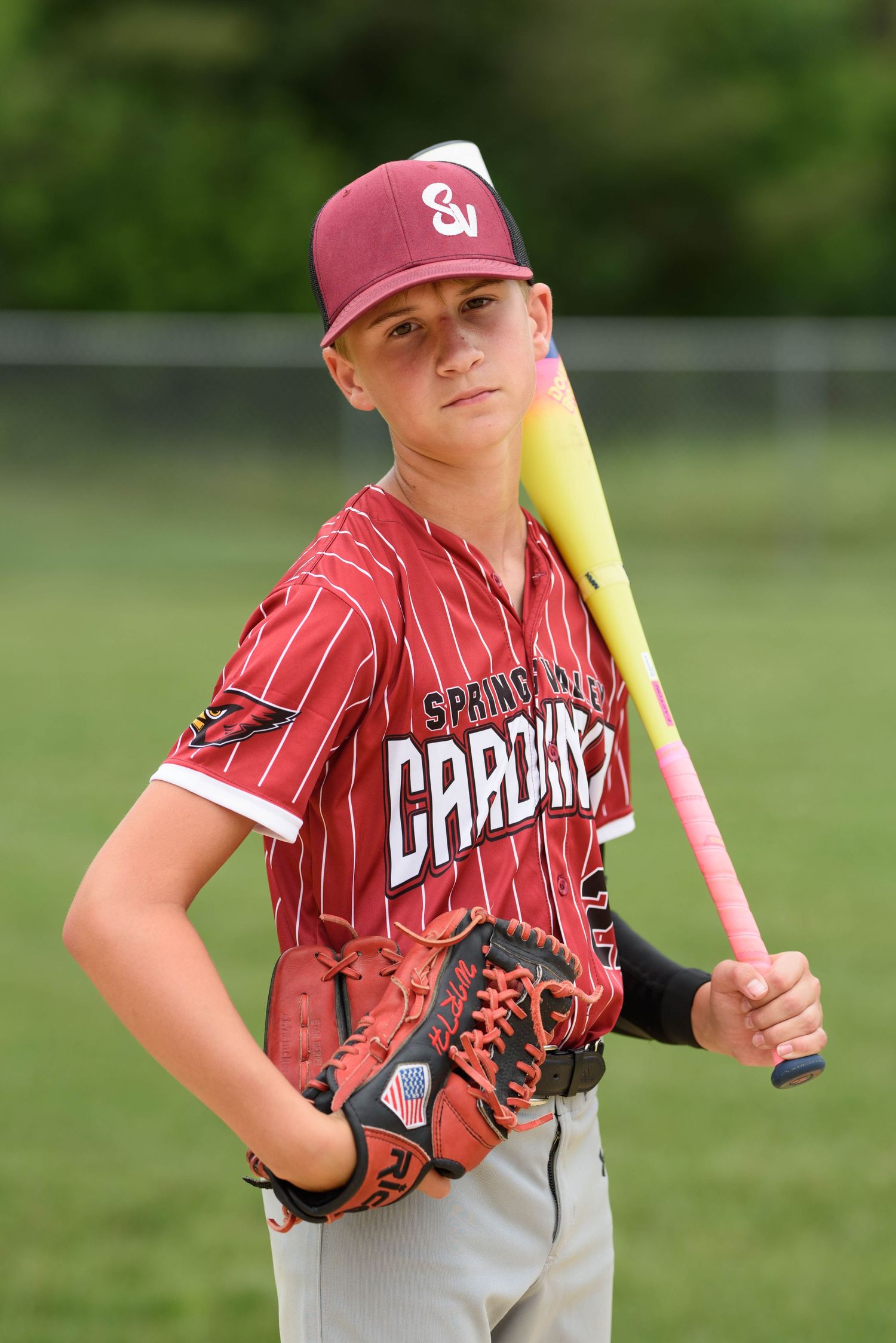 Youth baseball player in Spring Valley Cardinals uniform posing with yellow bat and glove on field.