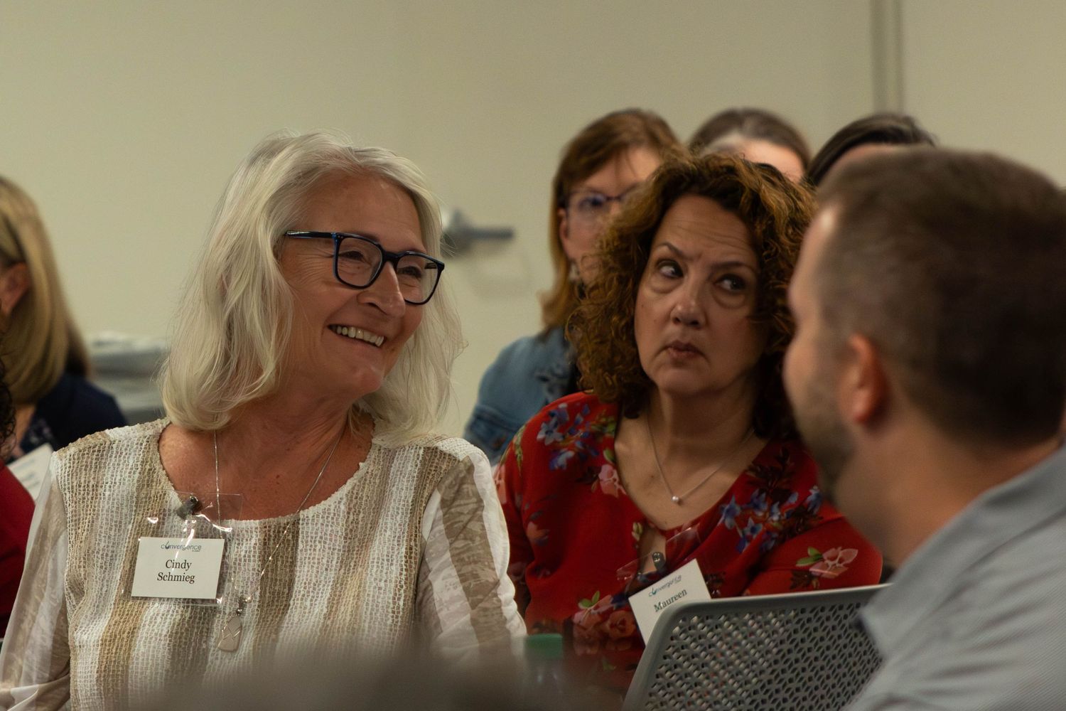 Group of professionals engaged in discussion at a conference or networking event, wearing name tags.