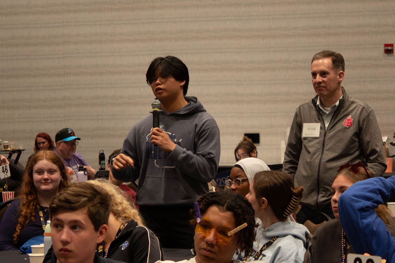 Student asking a question with microphone at a school leadership conference session.