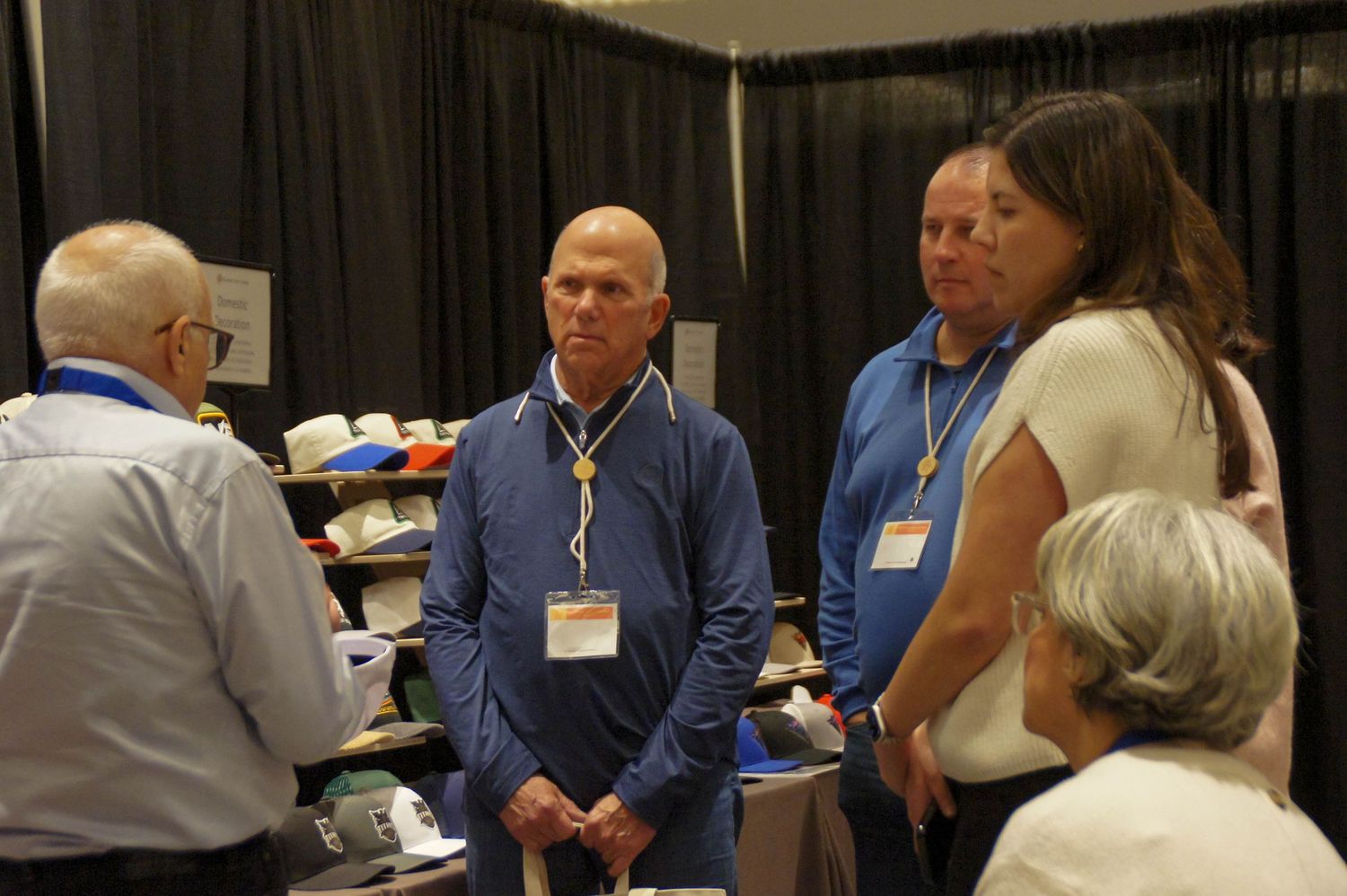Three professionals networking at an apparel trade show vendor booth.