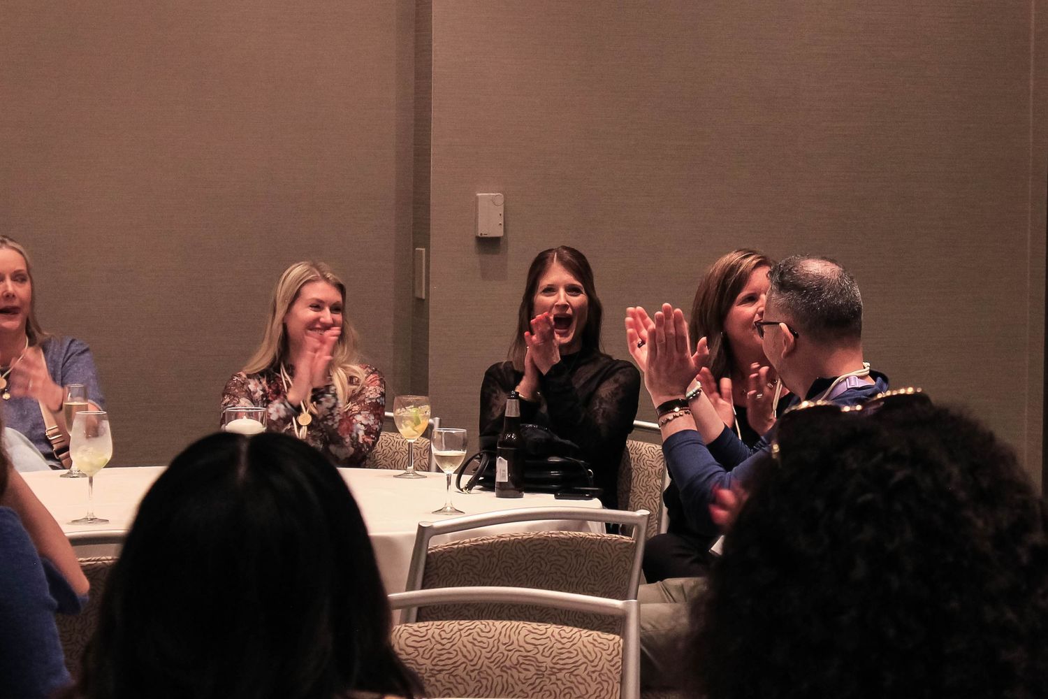 Group of people clapping and laughing at a conference banquet event.