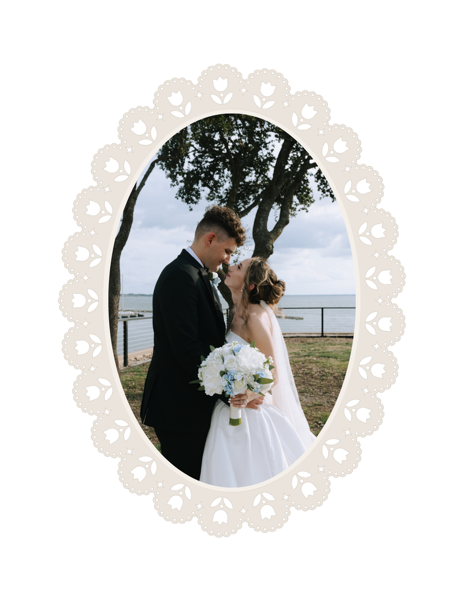 Bride and groom sharing a romantic moment outdoors near the water, framed by an elegant oval lace border.