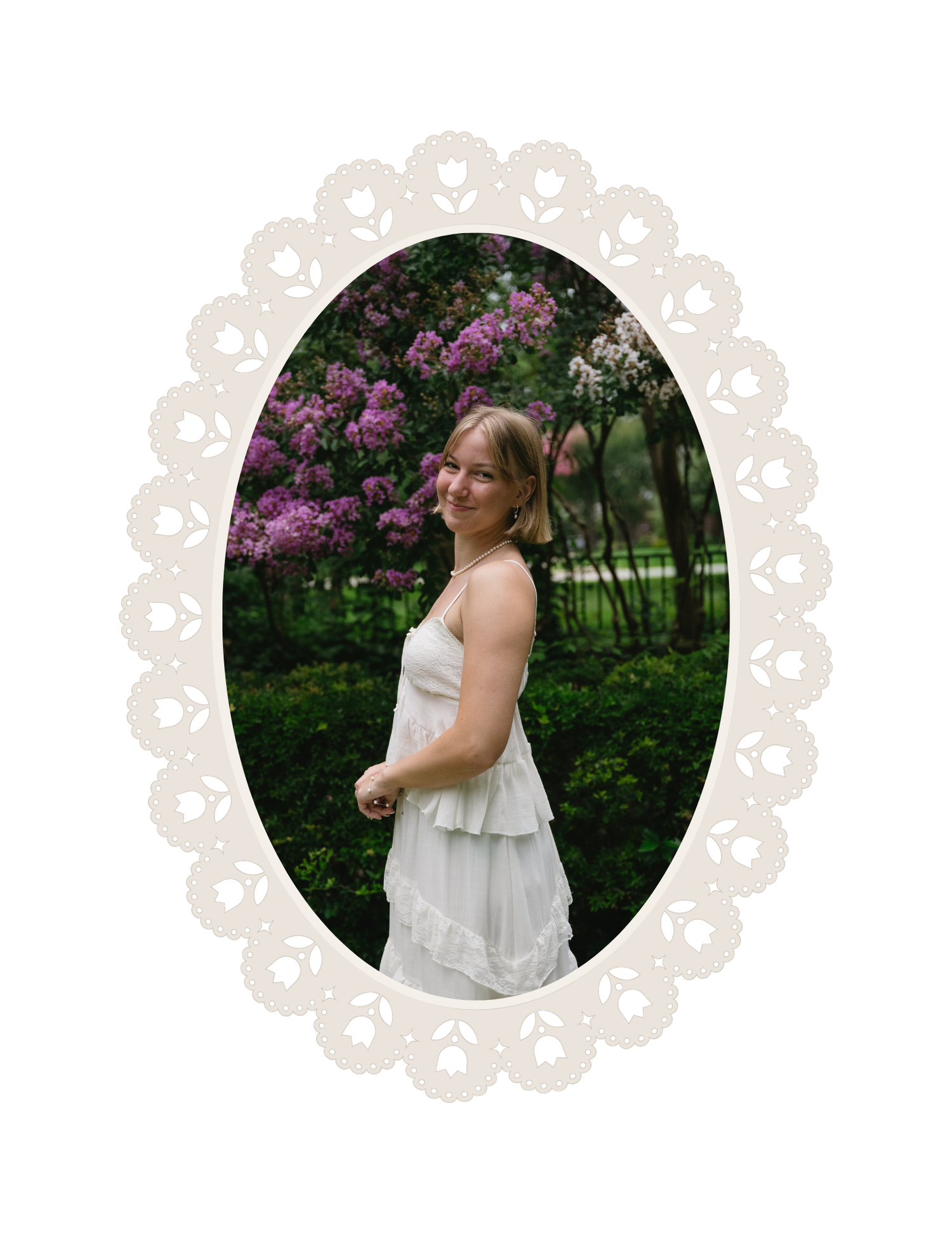 Young woman in white dress posing outdoors near blooming pink lilac trees, framed in decorative lace oval border.