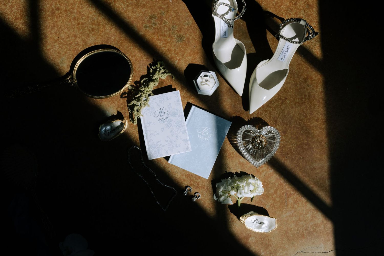 Elegant wedding stationery flat lay with invitations, candles, and heart-shaped crystal on a textured surface.