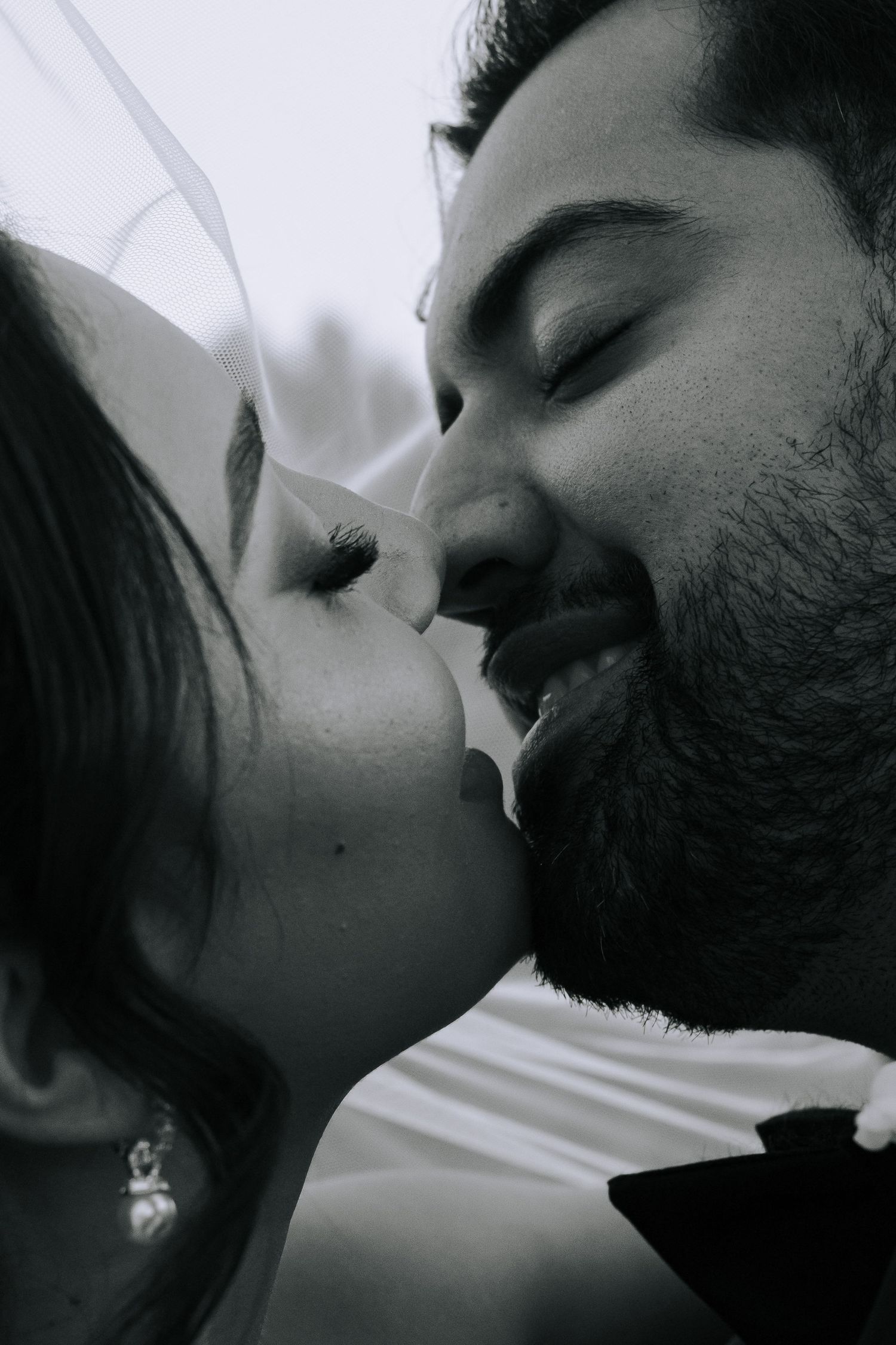 Intimate black and white close-up of a bride and groom sharing a tender kiss on their wedding day.
