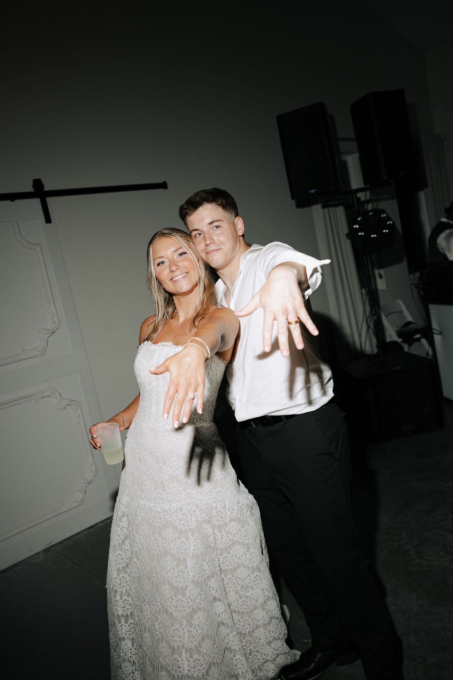 Newlyweds showing off wedding rings while dancing at their elegant indoor wedding reception.