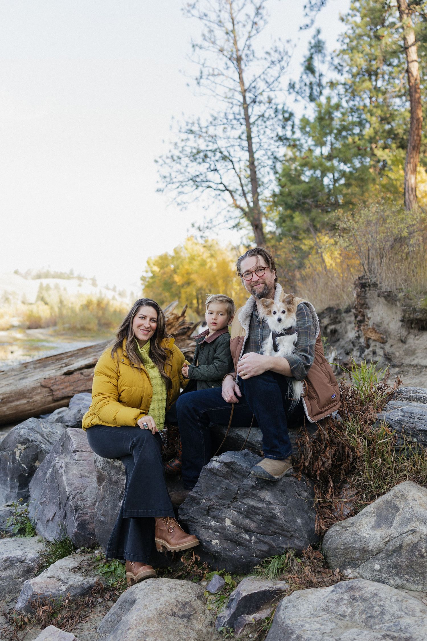 Family group sitting together on rocky outcrop in natural outdoor setting.