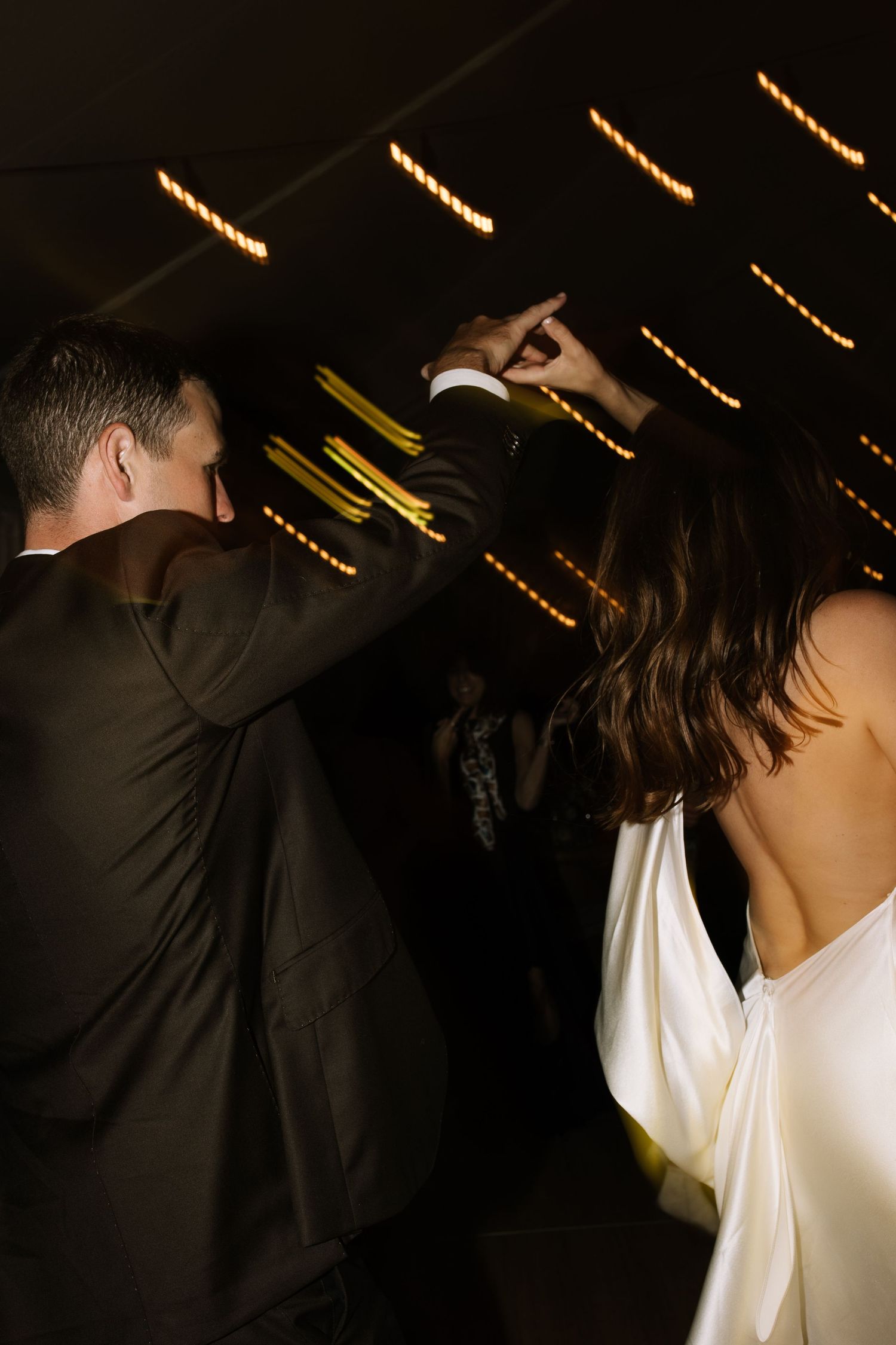Dancers moving beneath warm string lights at evening celebration.