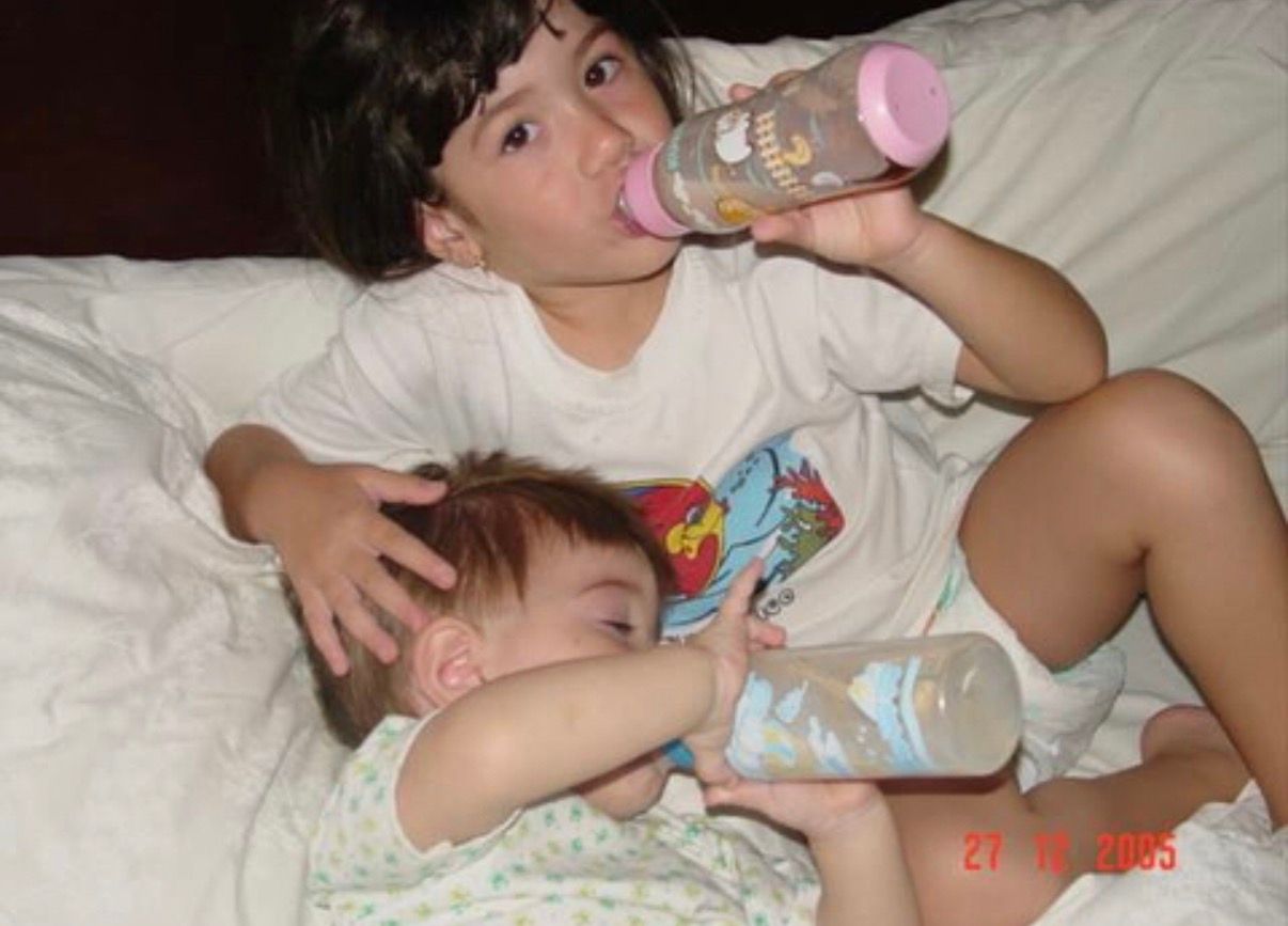 A baby lies on white bedding while drinking from a bottle, shown in a series of similar poses.