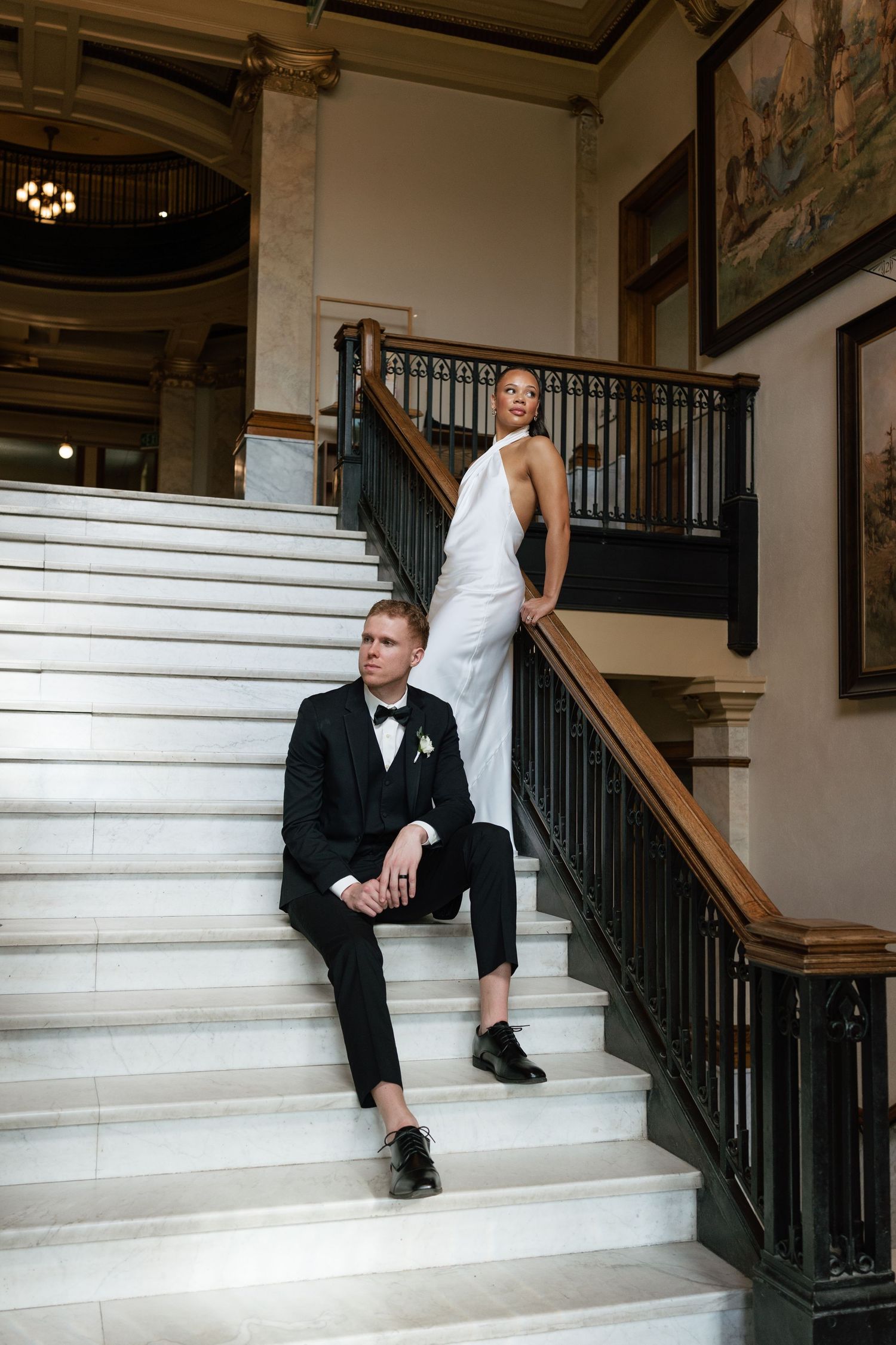 Wedding photo session on elegant white marble stairs with iron railings.