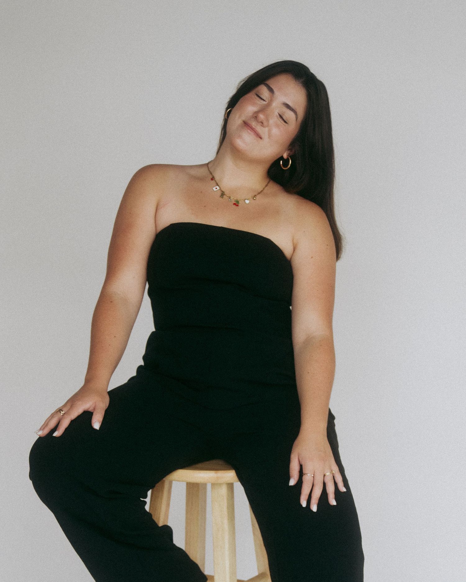 Fashion portraits of woman in black strapless dress against minimalist white backdrop.